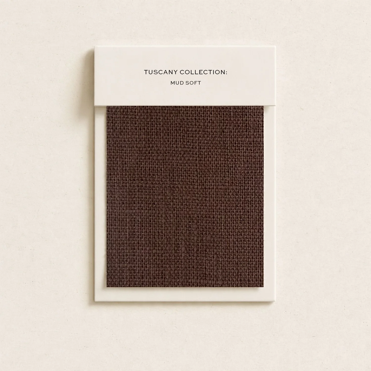 Sample swatch of dark brown fabric with textured weave, labeled 'Tuscany Collection: Mud Soft' on a white cardstock background.