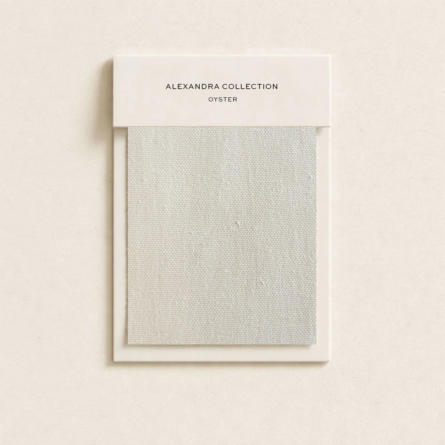 A white fabric sample card with a label reading 'ALEXANDRA COLLECTION OYSTER' at the top.