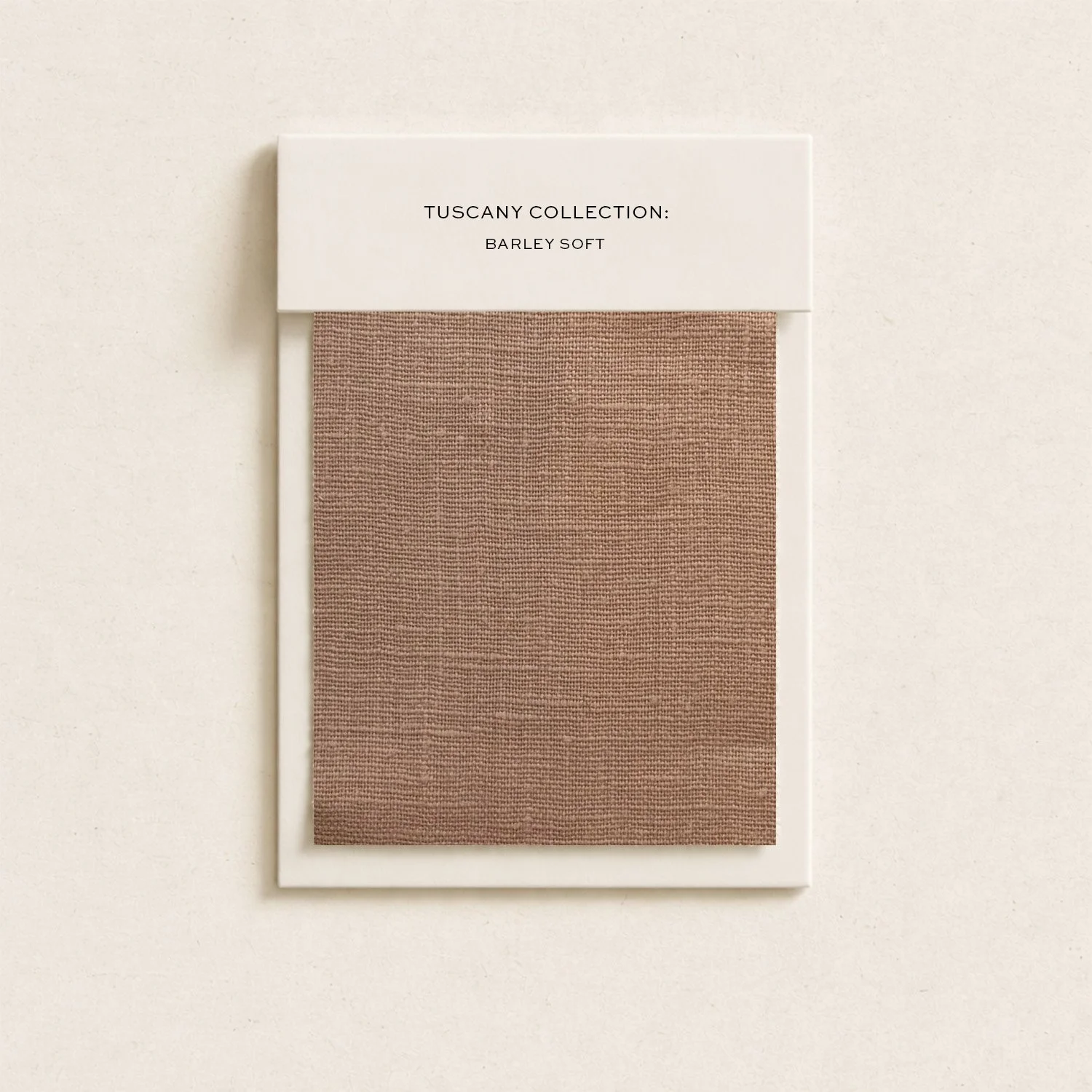 Sample swatch of beige fabric with a white label reading 'TUSCANY COLLECTION: BARLEY SOFT'