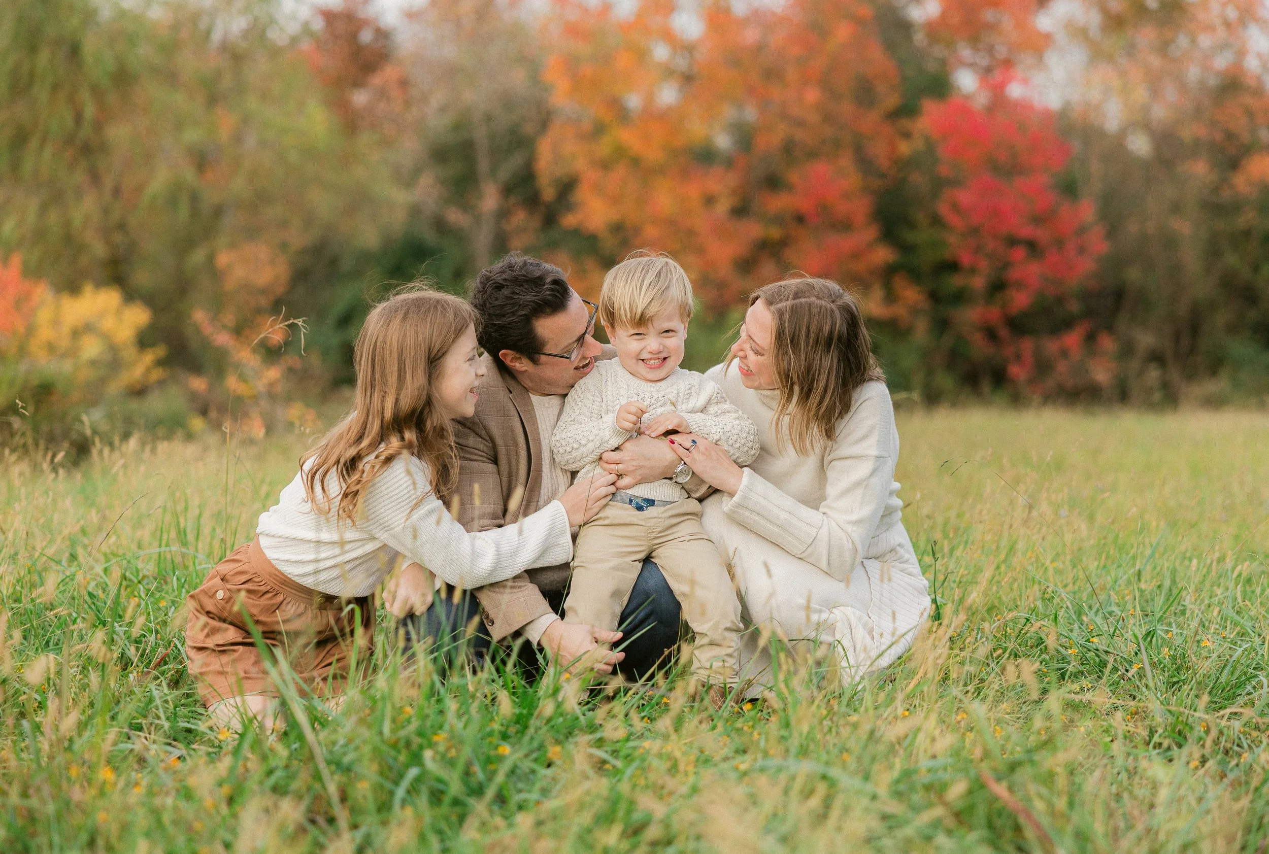 family smiling with fall colored background