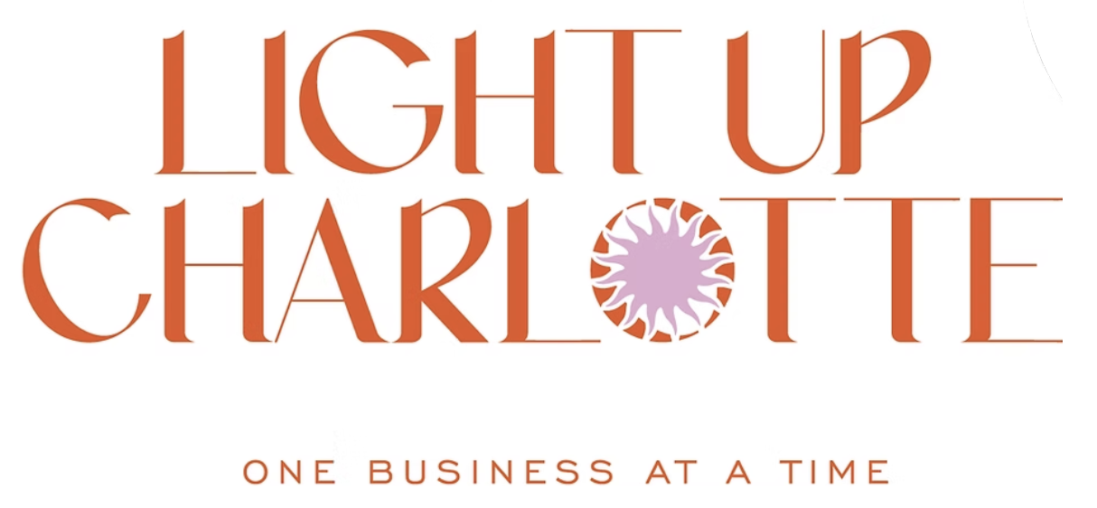 Logo for Light Up Charlotte with a pink and orange circular emblem in place of the 'O' in Charlotte, and the tagline 'One Business at a Time' underneath.