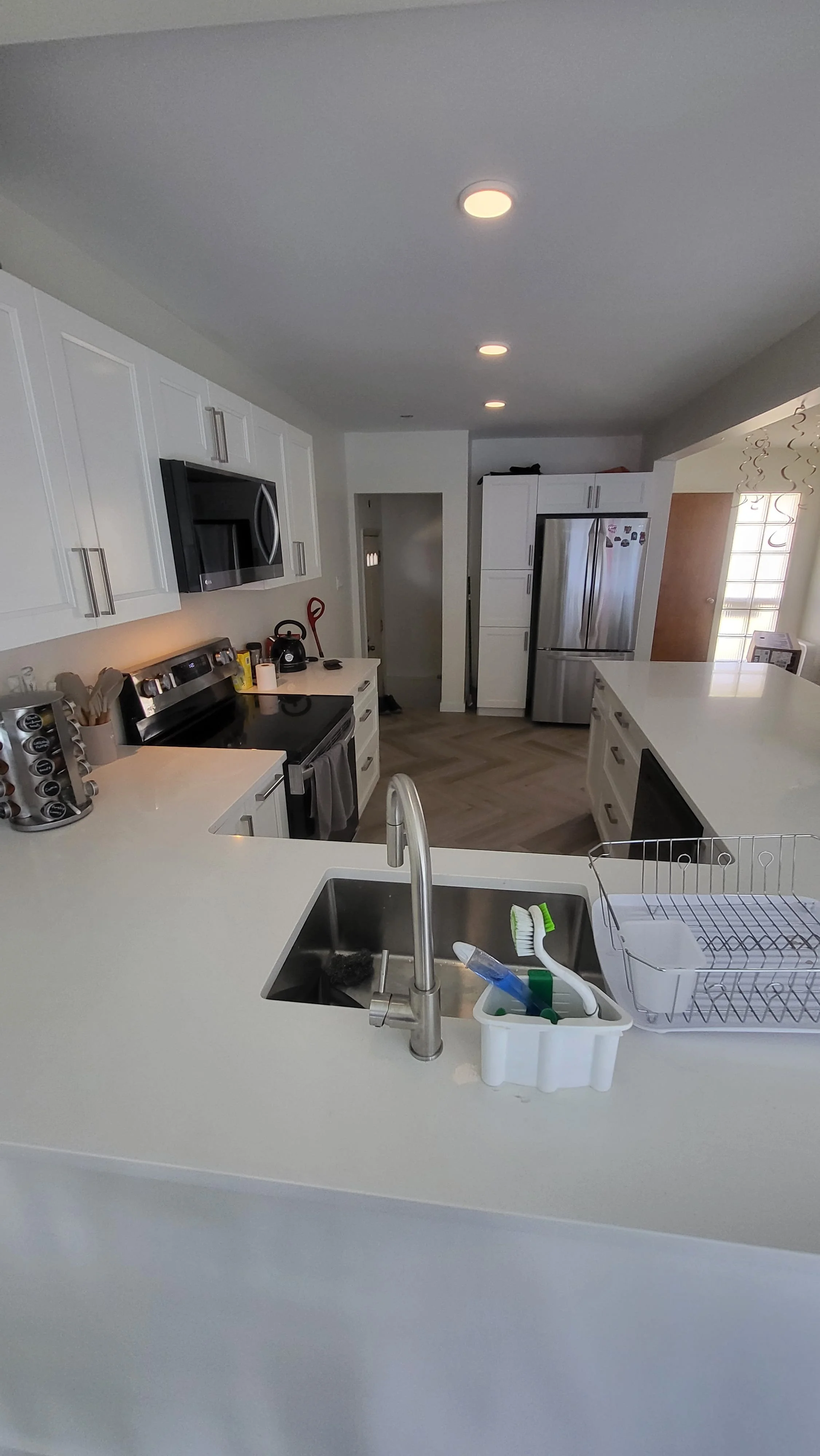 Modern kitchen with white cabinets, black appliances including a stove and microwave, a stainless steel refrigerator, and a white kitchen island with a sink. kitchen contractor, cabinet installer, appliance installer, drywall contractor, contractor.