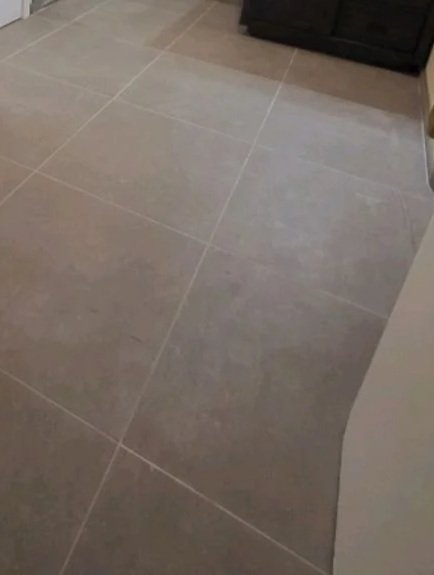 Close-up of a tiled floor in a room with dark-colored furniture in the background.