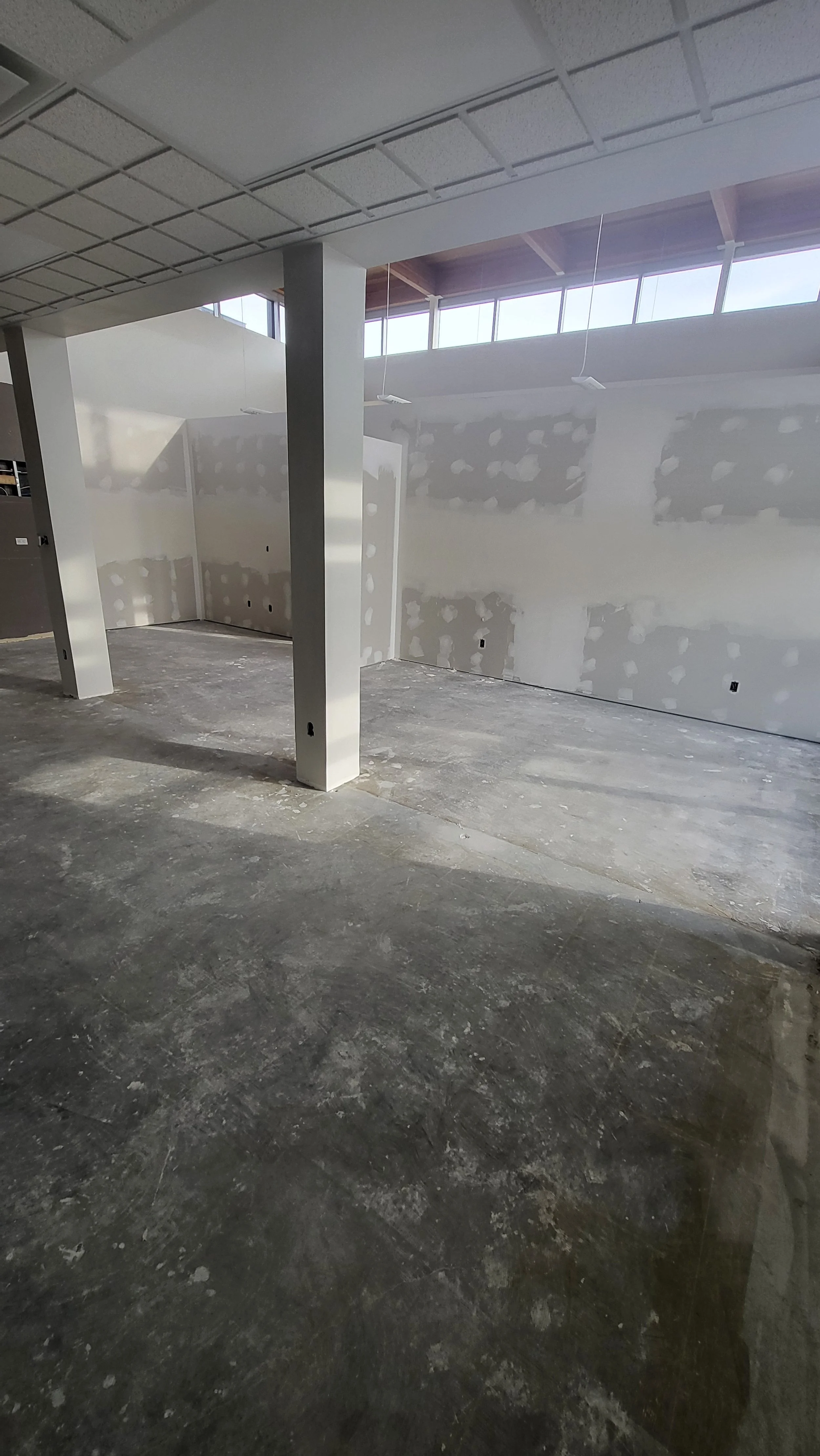 Interior of a building under construction or renovation with unfinished drywall walls and a concrete floor.