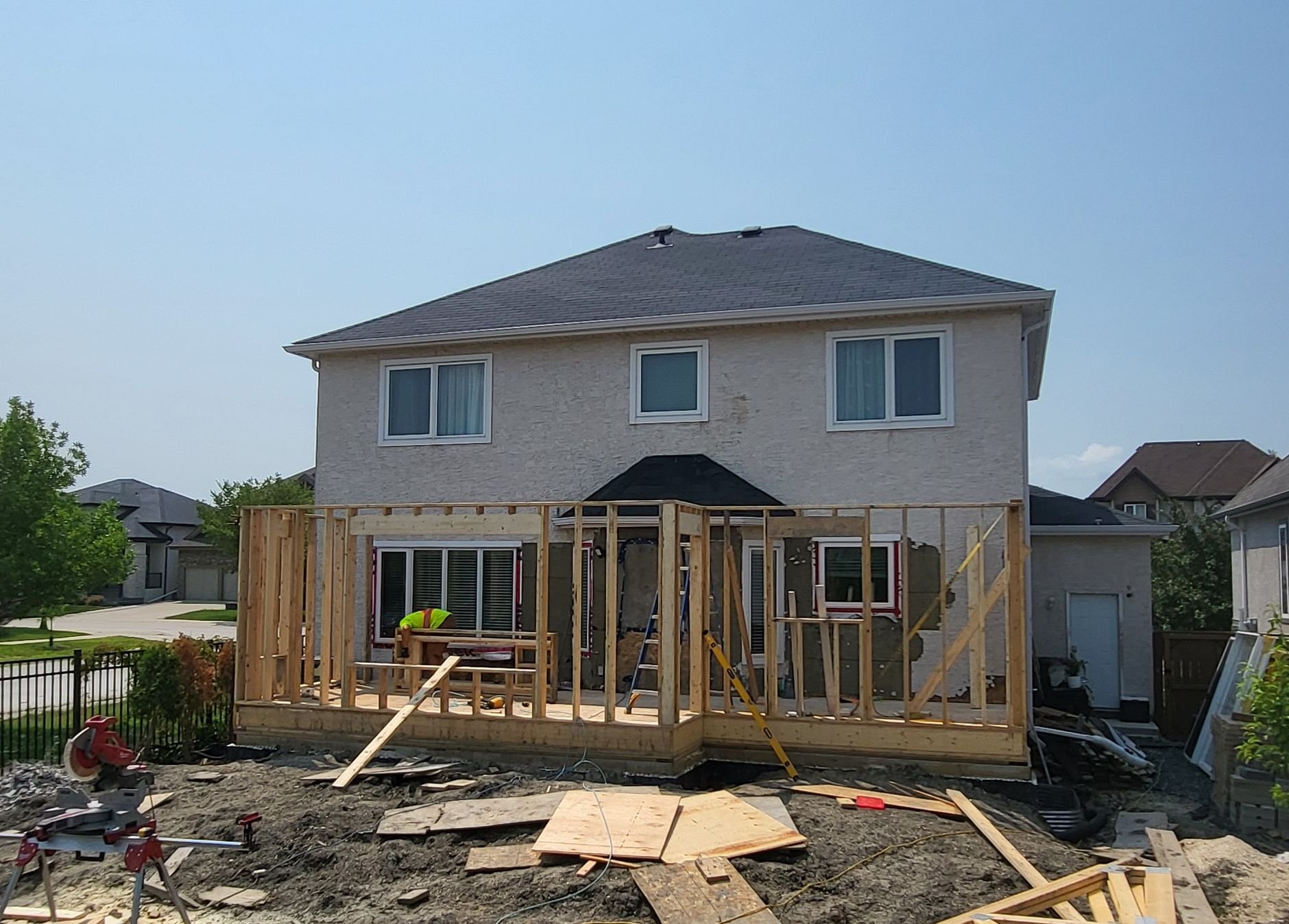 Residential house under construction with wooden framing on the back deck and construction worker working.