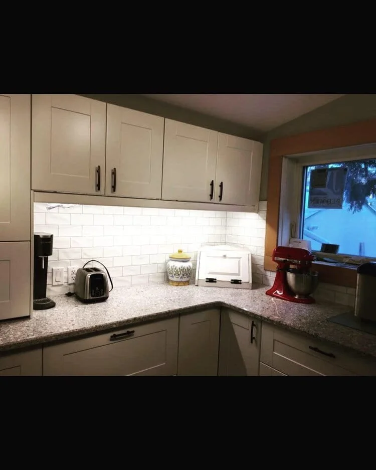 Kitchen countertop with coffee maker, toaster, decorative jar, bread box, and red stand mixer near a window with a view outside. kitchen contractor, cabinet installer, appliance installer, drywall contractor, contractor.