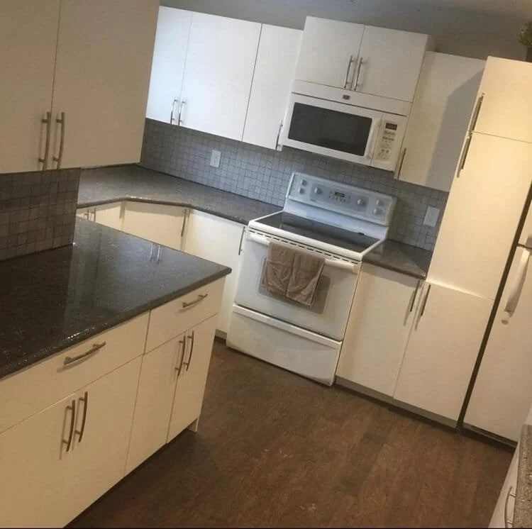 Modern kitchen with white cabinets, black granite countertops, a white stove with an oven, and a microwave above the stove. kitchen contractor, cabinet installer, appliance installer, drywall contractor, contractor.