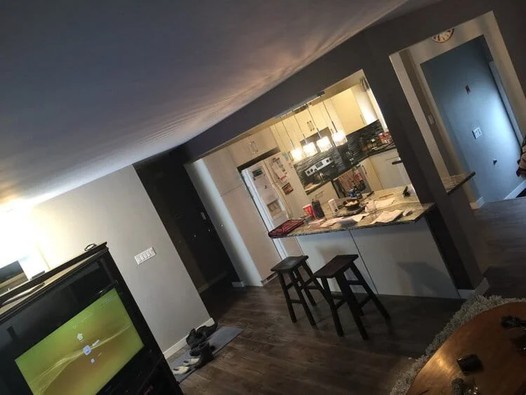 Open kitchen and living room in a home with a television, dining table, and stools at the counter. kitchen contractor, cabinet installer, appliance installer, drywall contractor, contractor.