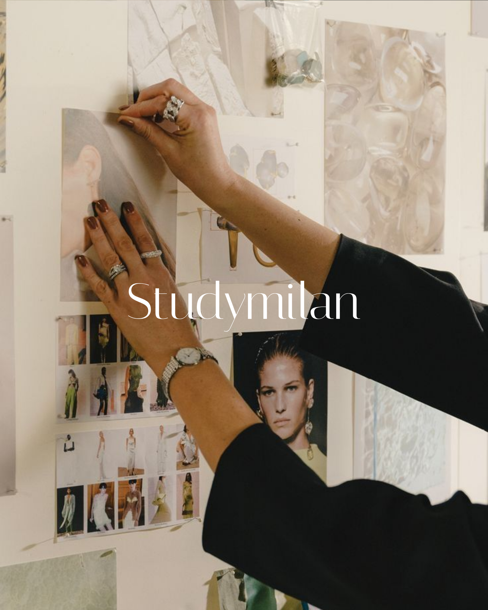 Manos ajustando fotos y muestras de diseño en una pared, con varias fotos de modelos en ropa de moda y collares, en un ambiente de estudio o diseño de moda.
