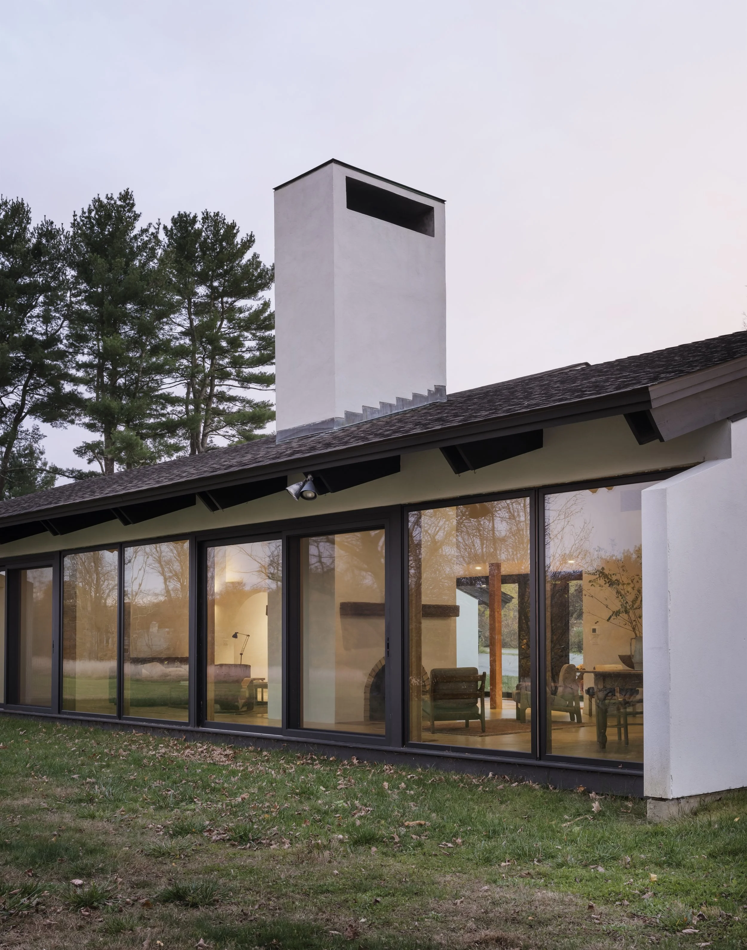 Mid century house in a field surrounded by pine trees