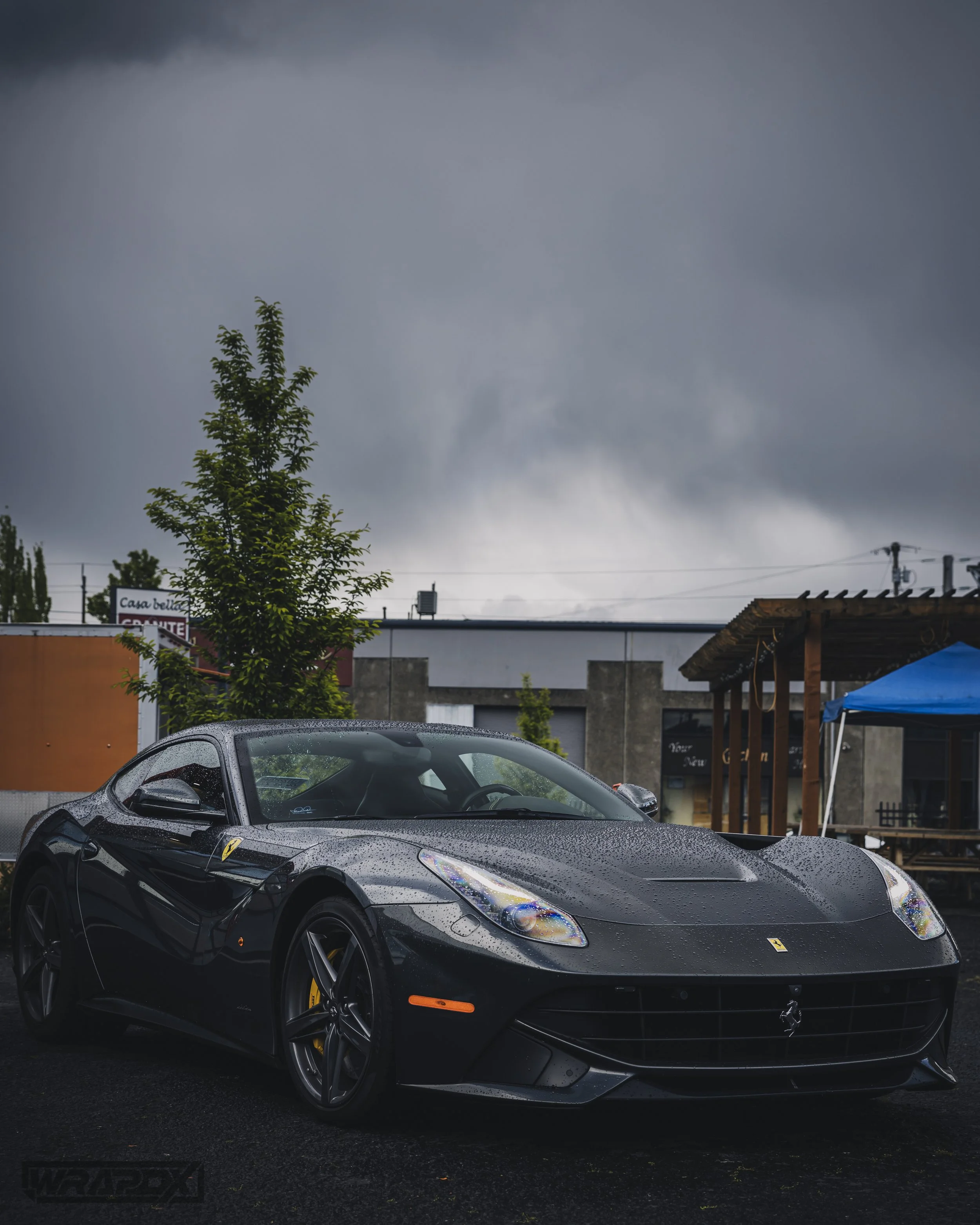 Luxury sports car parked outdoors on a rainy day.