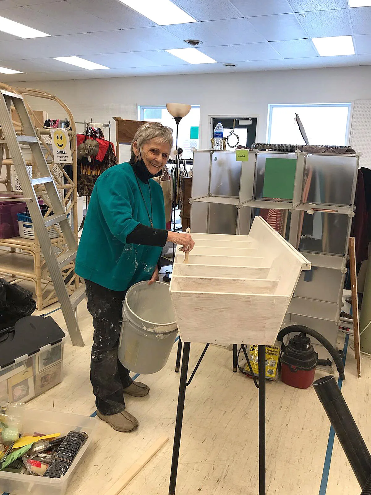 A volunteer applies a coat of paint to some bins.