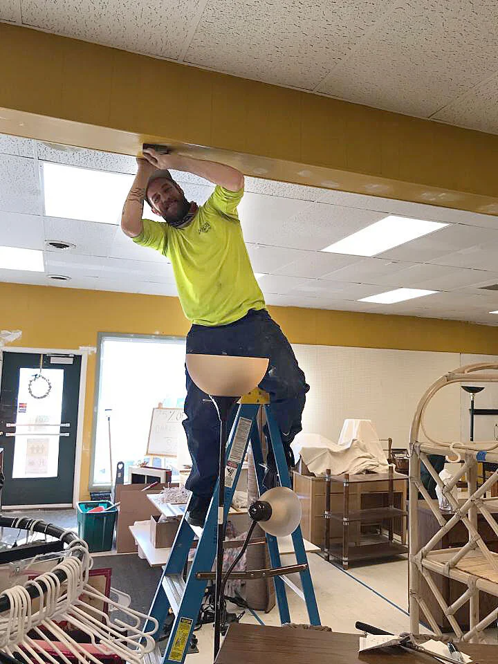 Repairing the facing on a beam inside the Thrift Store.