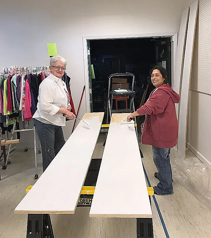 Volunteers painting two shelves for the Thrift Store.