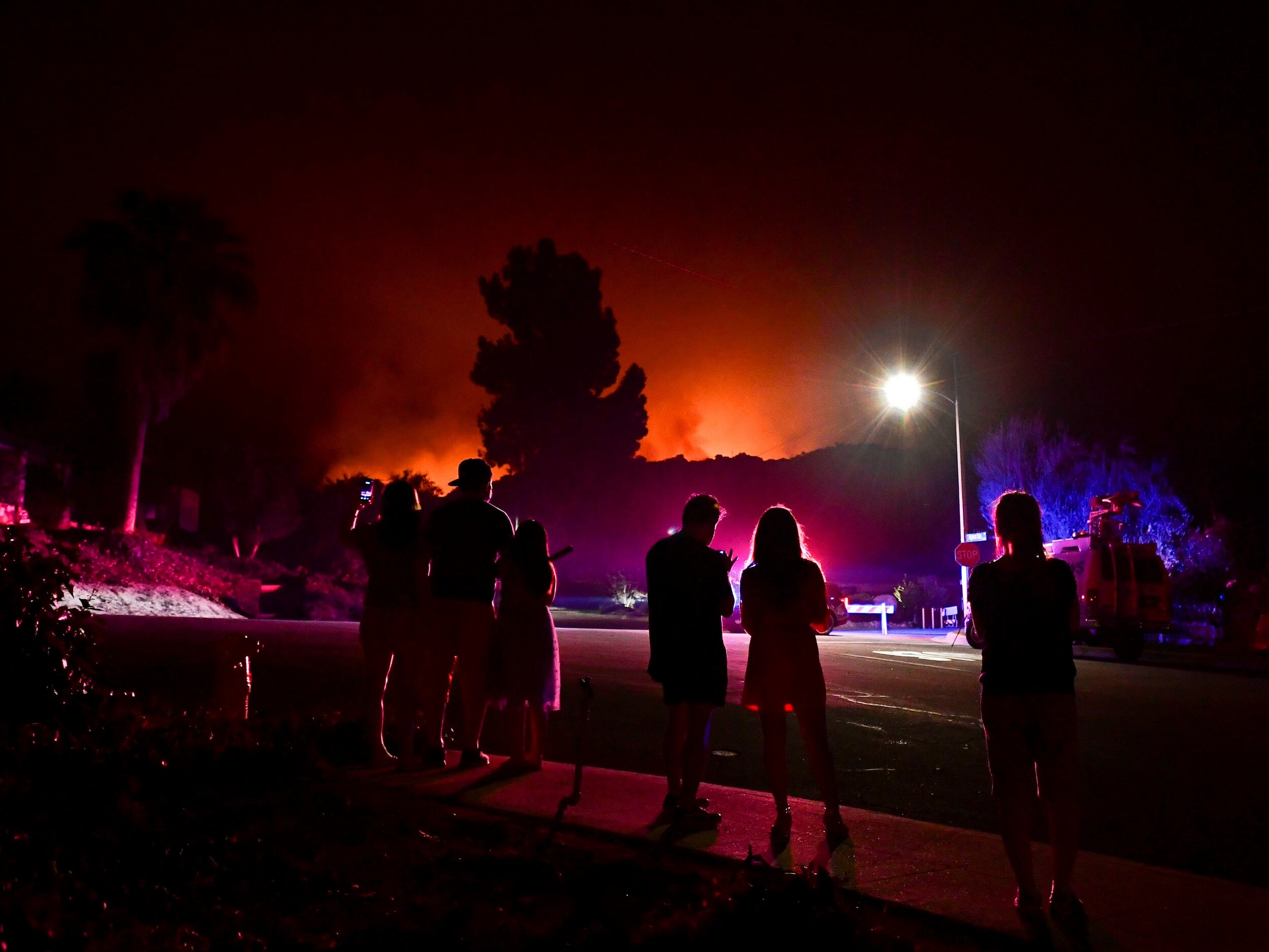 People watch as the Bobcat Fire burns on hillsides behind homes in Arcadia, California on September 13, 2020. (Frederic J. Brown / AFP via Getty Images)