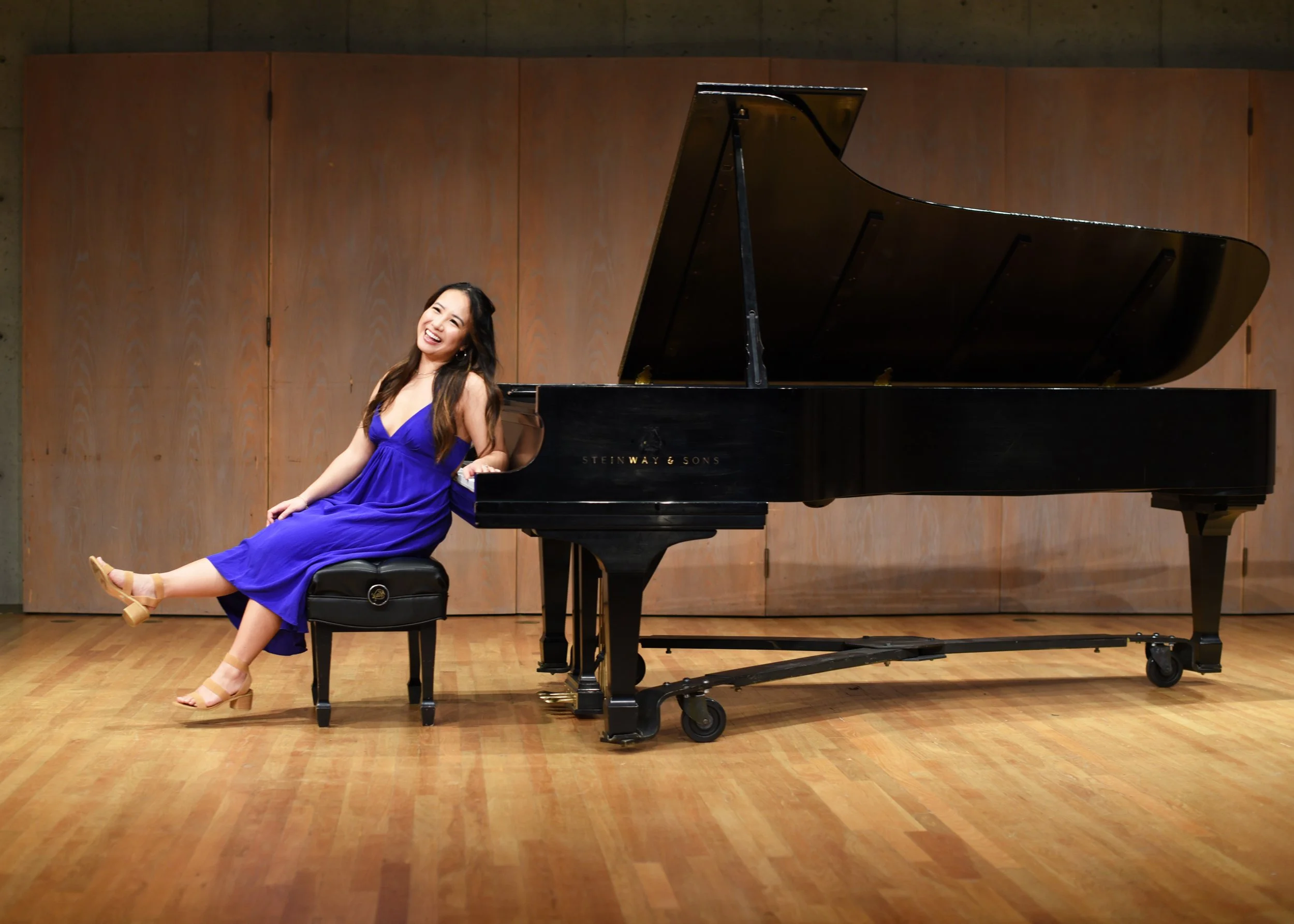 Grad wearing blue dress sitting at piano for photoshoot