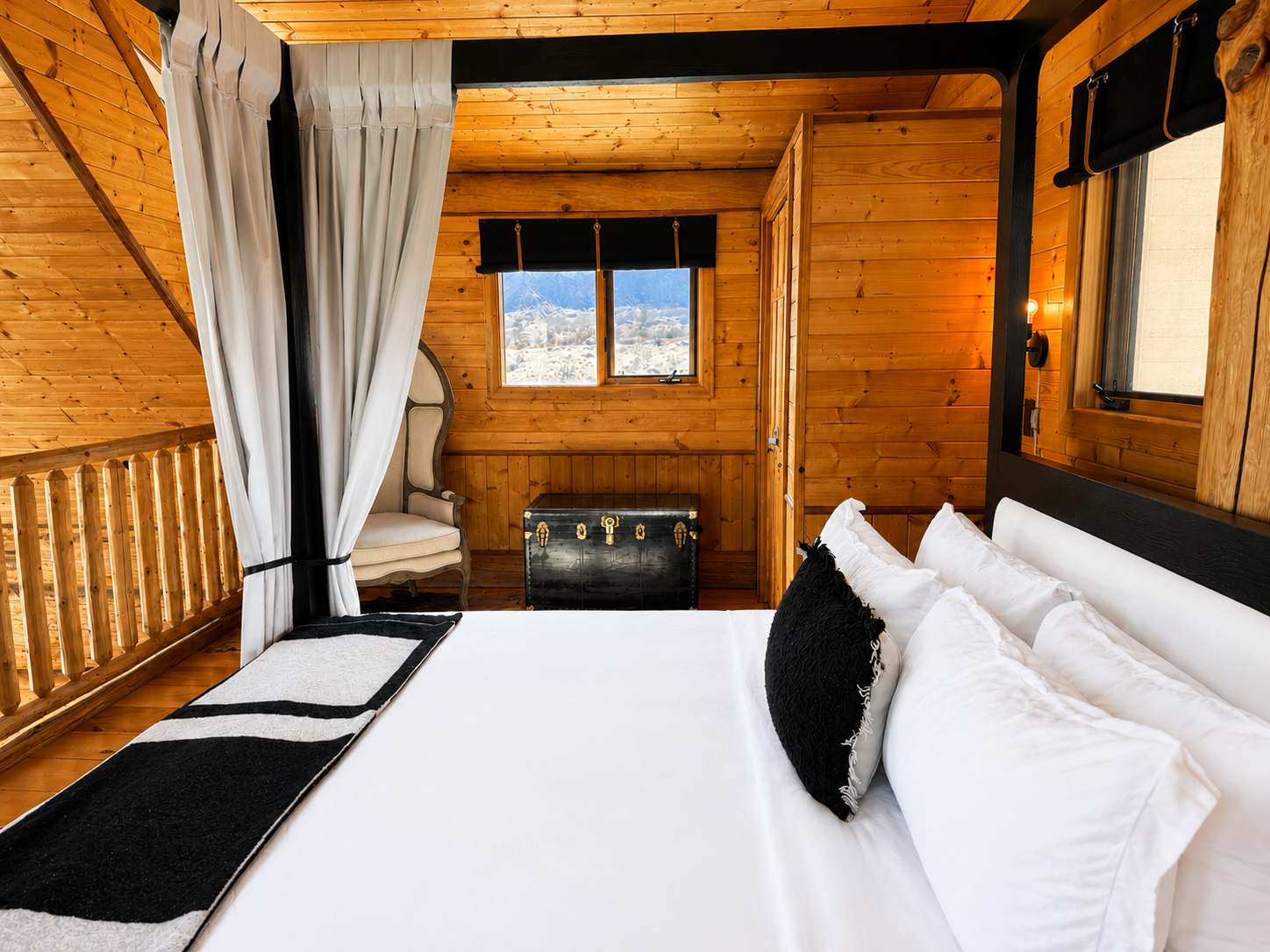 Cabin bedroom with windows on both sides of the bed and desert views