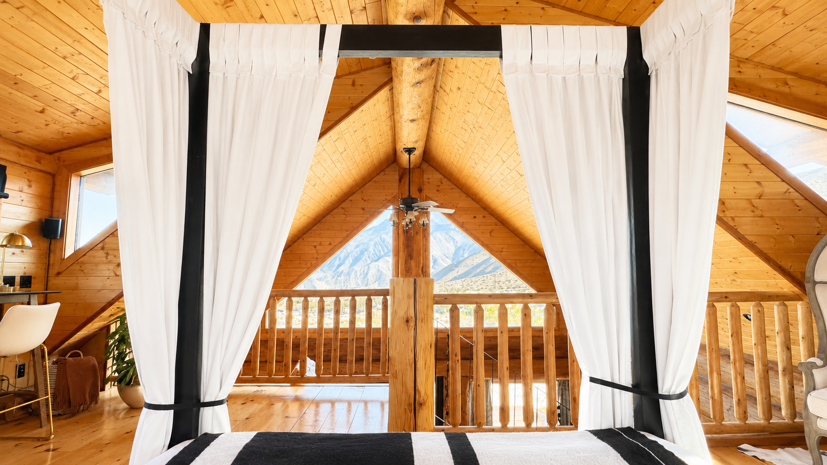 Loft bedroom looking down the A-frame to the gable window and mountains