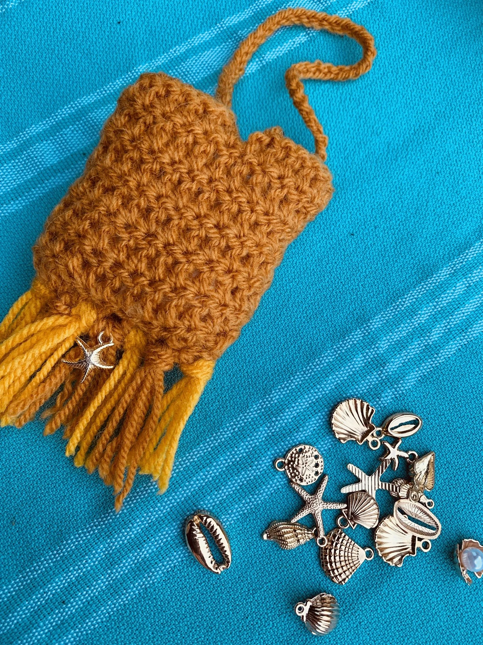 Gehaakt beschermhoesje voor
 airpods afgewerkt met franjes en 
een bedeltje☀️🐚