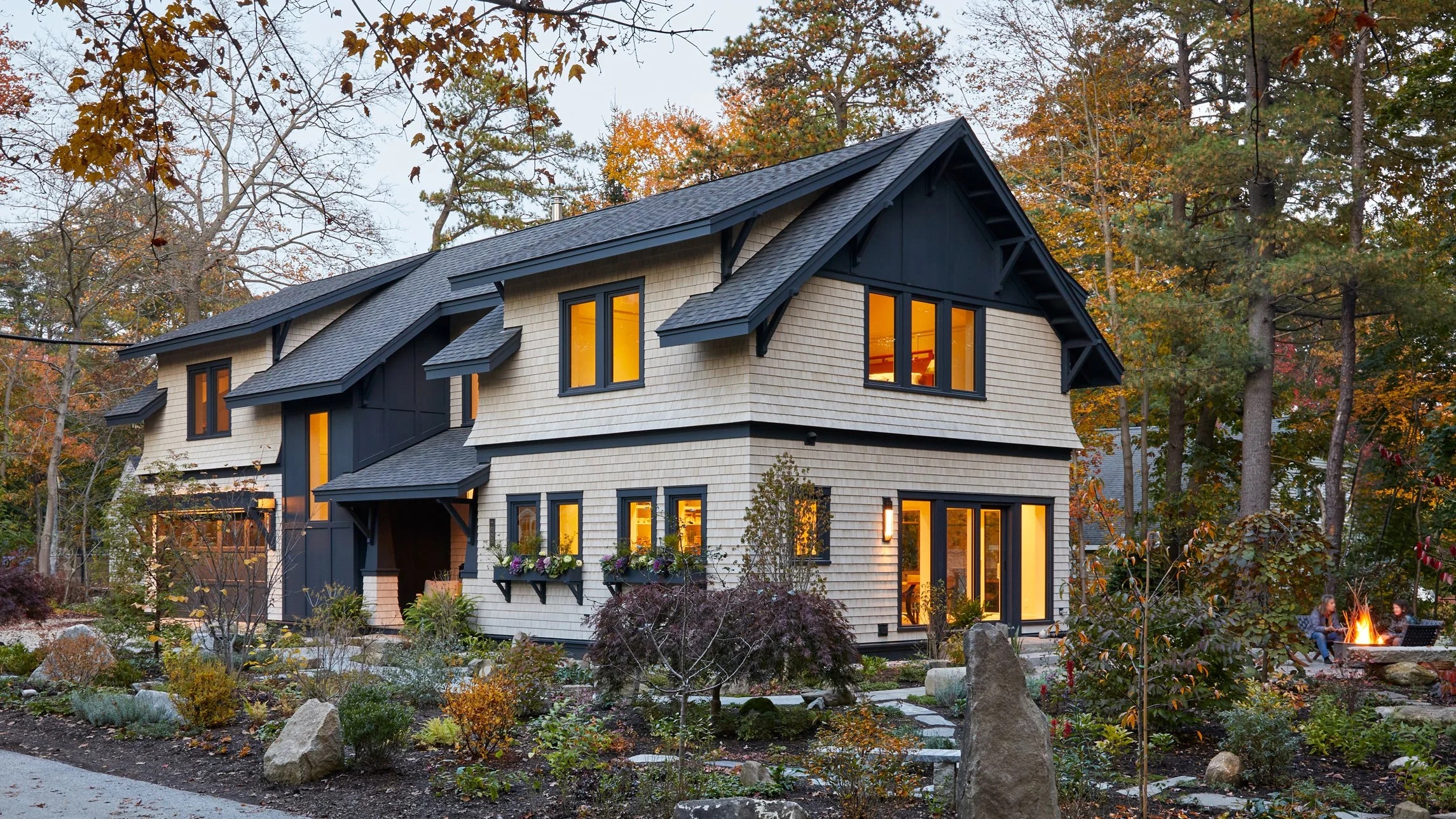 Timber-framed residence with a gabled roof, surrounded by dense forest in Maine.