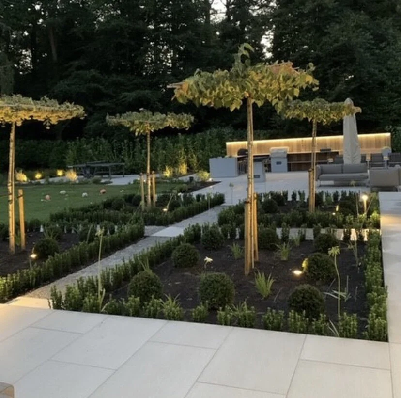 Modern backyard patio with small trees, garden beds, outdoor seating, illuminated planting areas really finishes this space