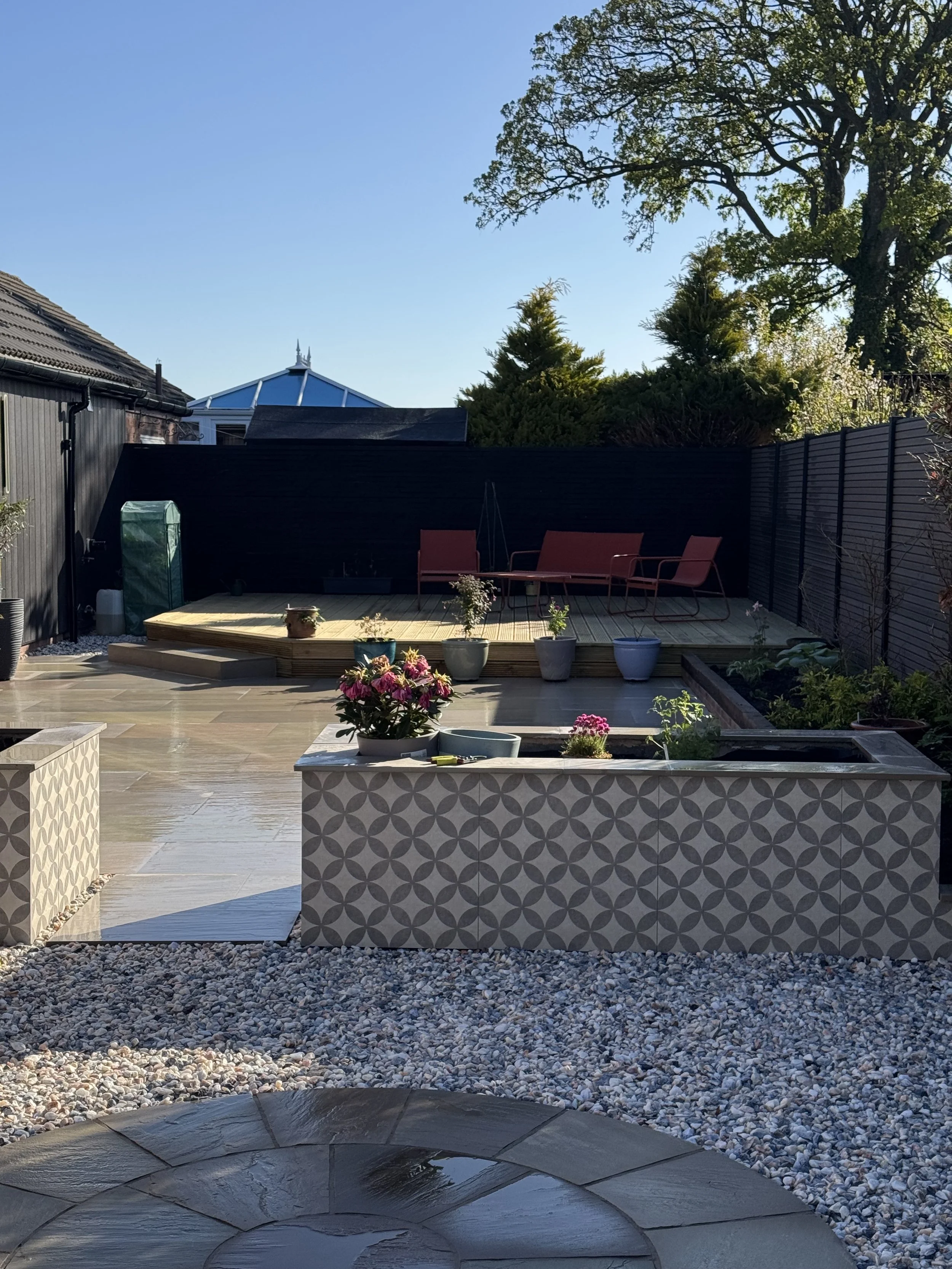 A mixture of softwood decking porcelain paving composite fencing and raised planters really transformed this space