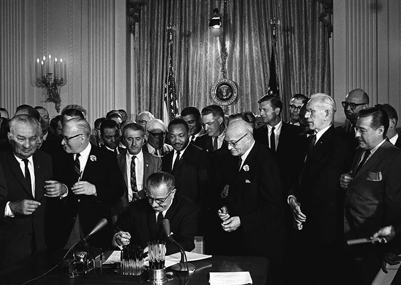 Lyndon Johnson signs the Social Security Amendments of 1965, creating Medicaid and Medicare.