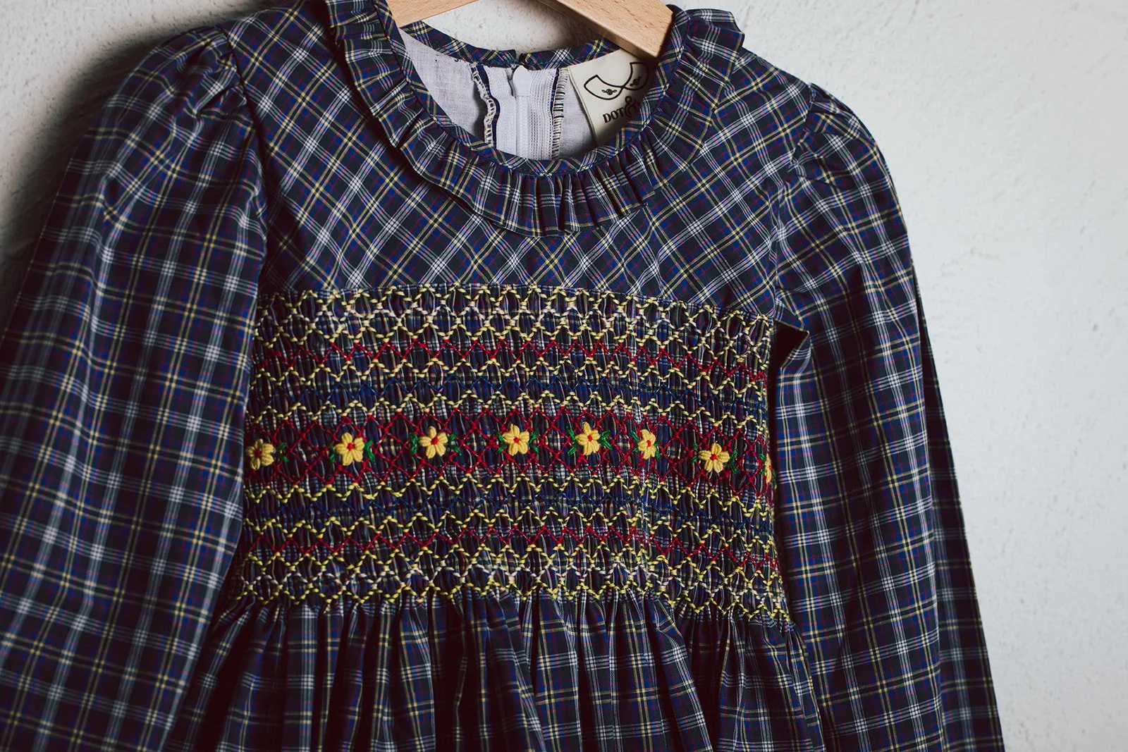 Hand-smocked check long sleeve winter dress with embroidery by Dot & Mila.