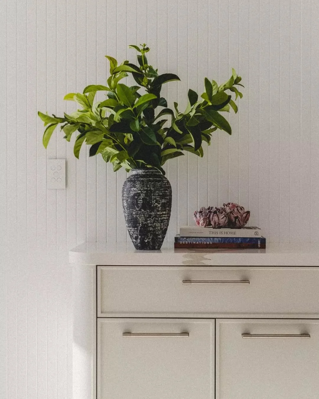 UNDERSTATED ELEGANCE &bull; The entry joinery to Penthouse P sets the tone with its curved-edge joinery, walls clad in white slimline v-groove panels, and thin shaker-style cabinetry. Topped with an engineered stone benchtop, this cabinetry seamlessl