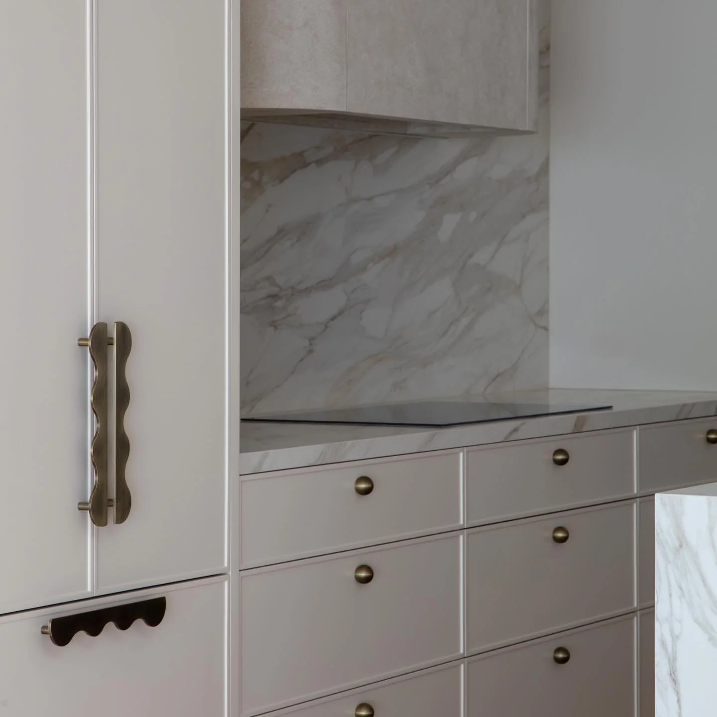 SERENE STATE &bull; Anchored by a sculptural stone island, the Grandview kitchen embodies quiet, considered luxury. Seamless cabinetry conceals functionality, while the softly textured rangehood introduces a gentle, refined depth. Crisp white pendant