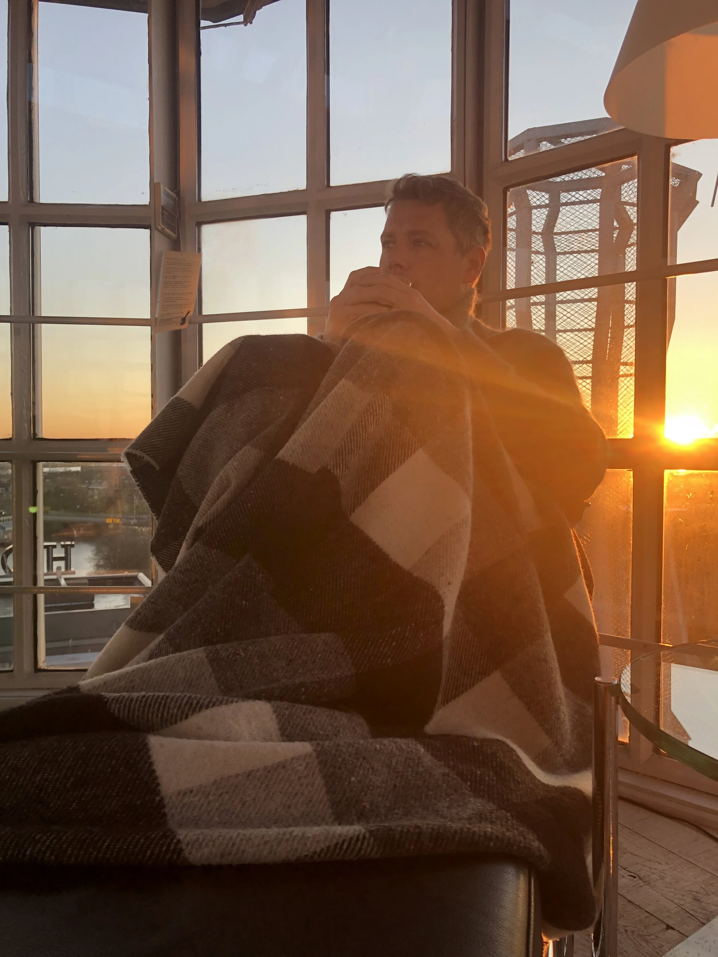 Me enjoying the first cup of the morning in our room at Villa Augustus in Dordrecht, The Netherlands while the sun is rising. A really cold morning but nothing keeps you warm like a woollen blanket and a hot cup of coffee.