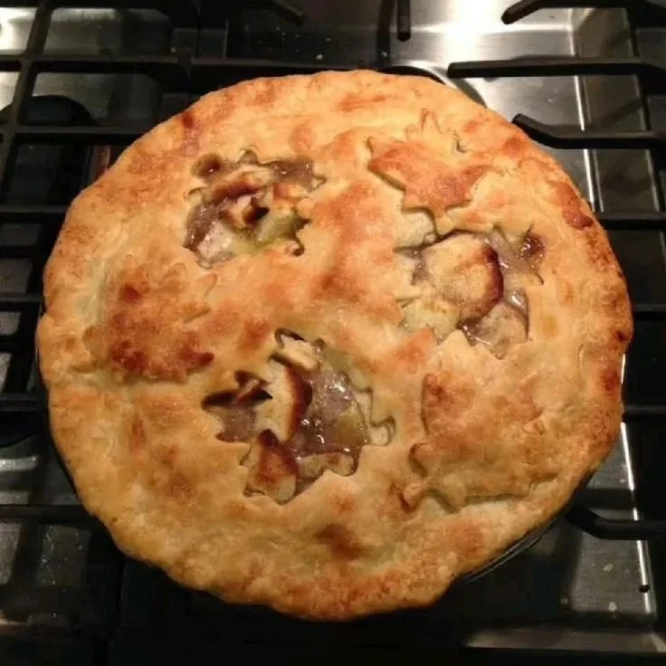 Apple pie with a golden autumn leaf patterned crust.