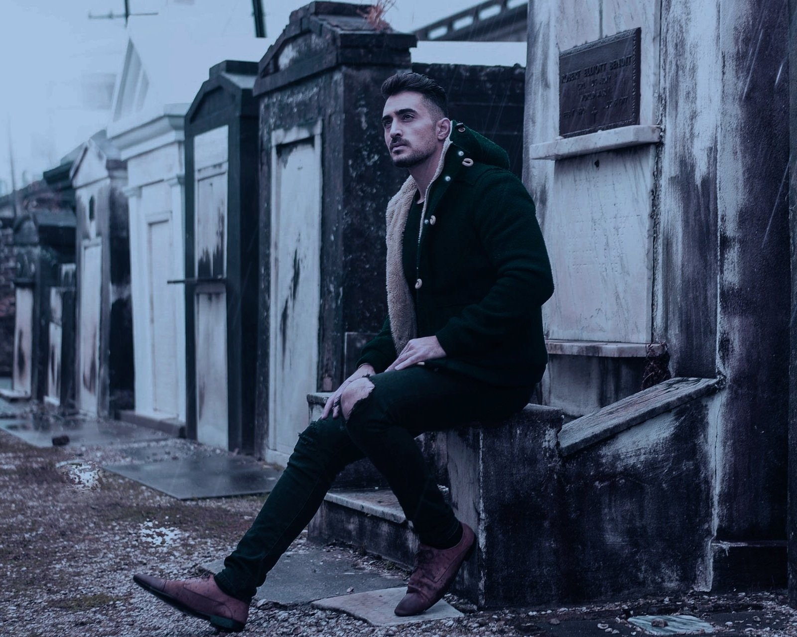 Man resting at a mausoleum in New Orleans cemetery.