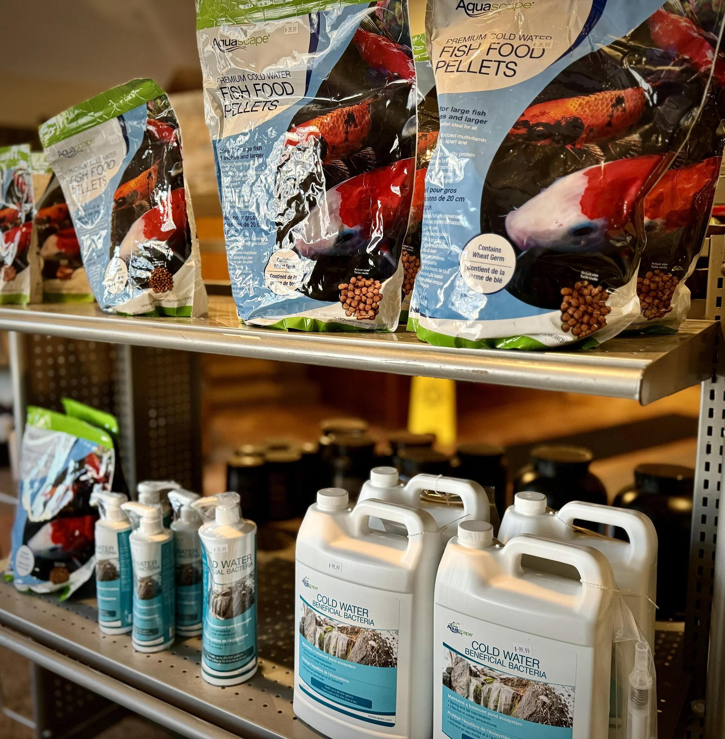 Shelves with bags of fish food pellets and bottles of beneficial bacteria for ponds in a store.