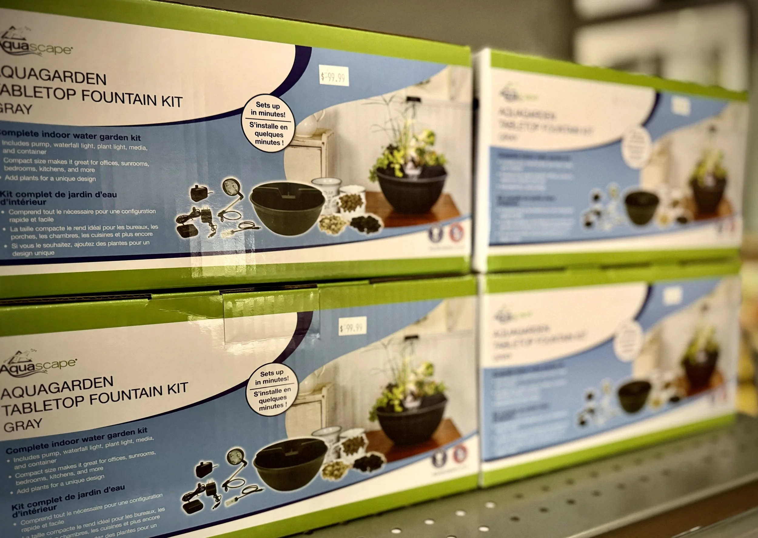 Box of AquaScape Aquagarden tabletop fountain kit in gray, with an image of a small indoor water garden with a black bowl, a potted plant, and accessories. Price is $99.99.