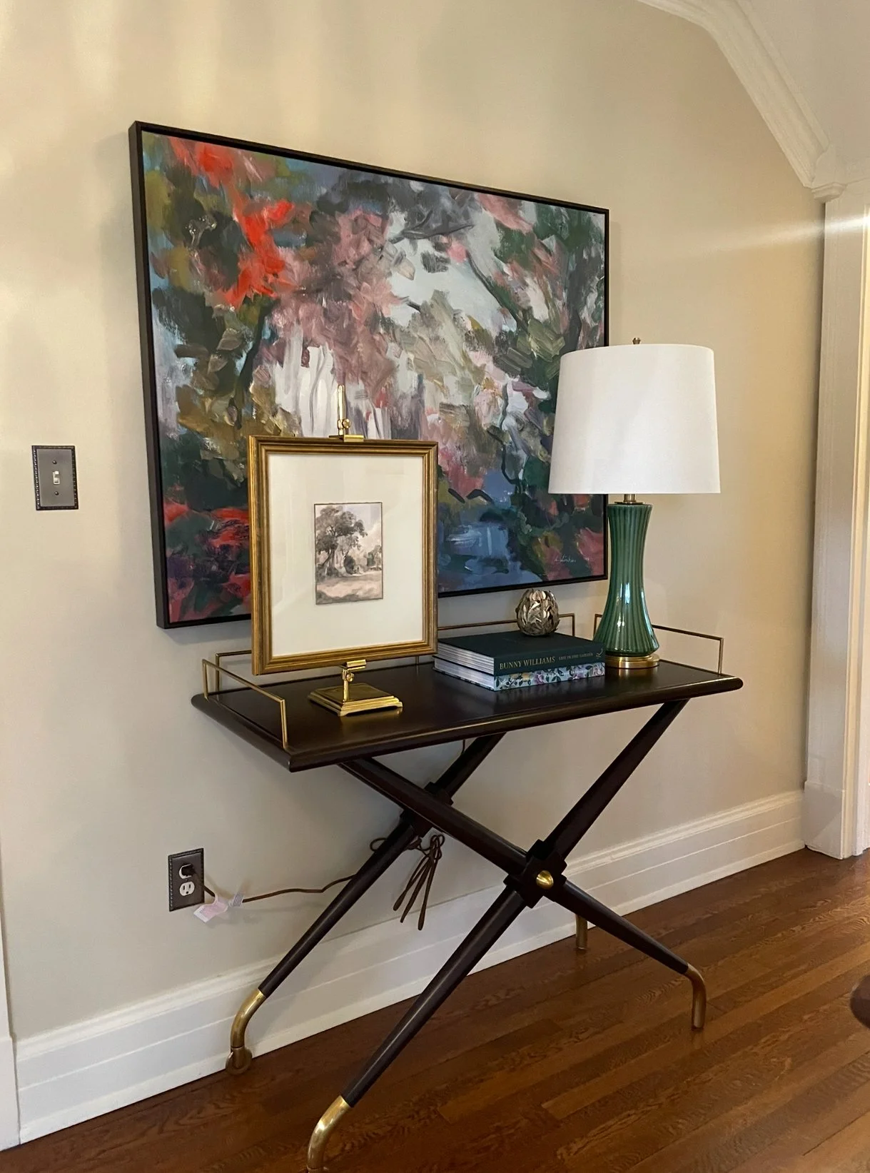 Classic staircase entryway with white balusters, wooden handrail, upholstered bench, framed artwork, and rich hardwood floors.