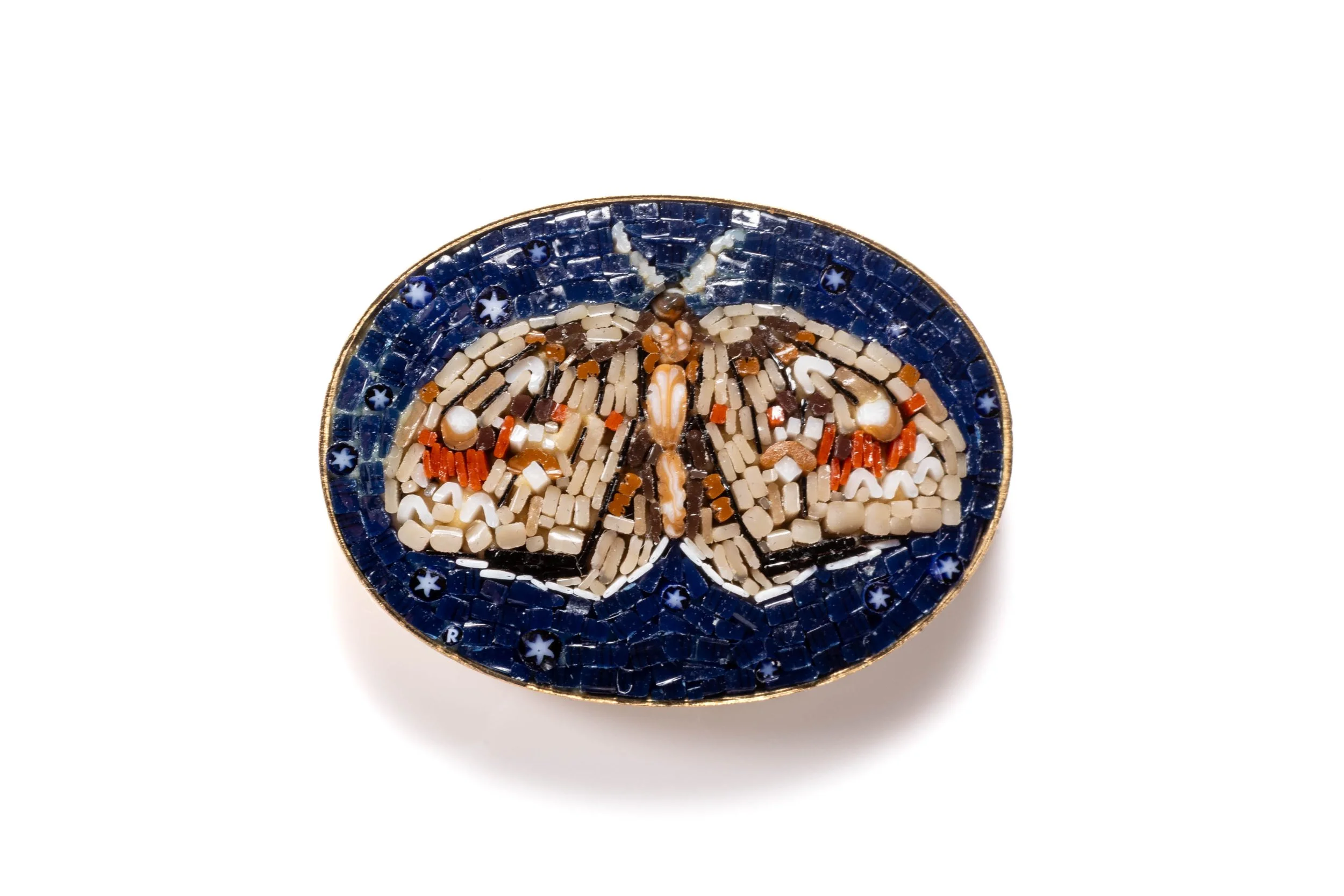 Moth with cream and brown wings and red markings in an oval micromosaic cabochon on a deep blue background.