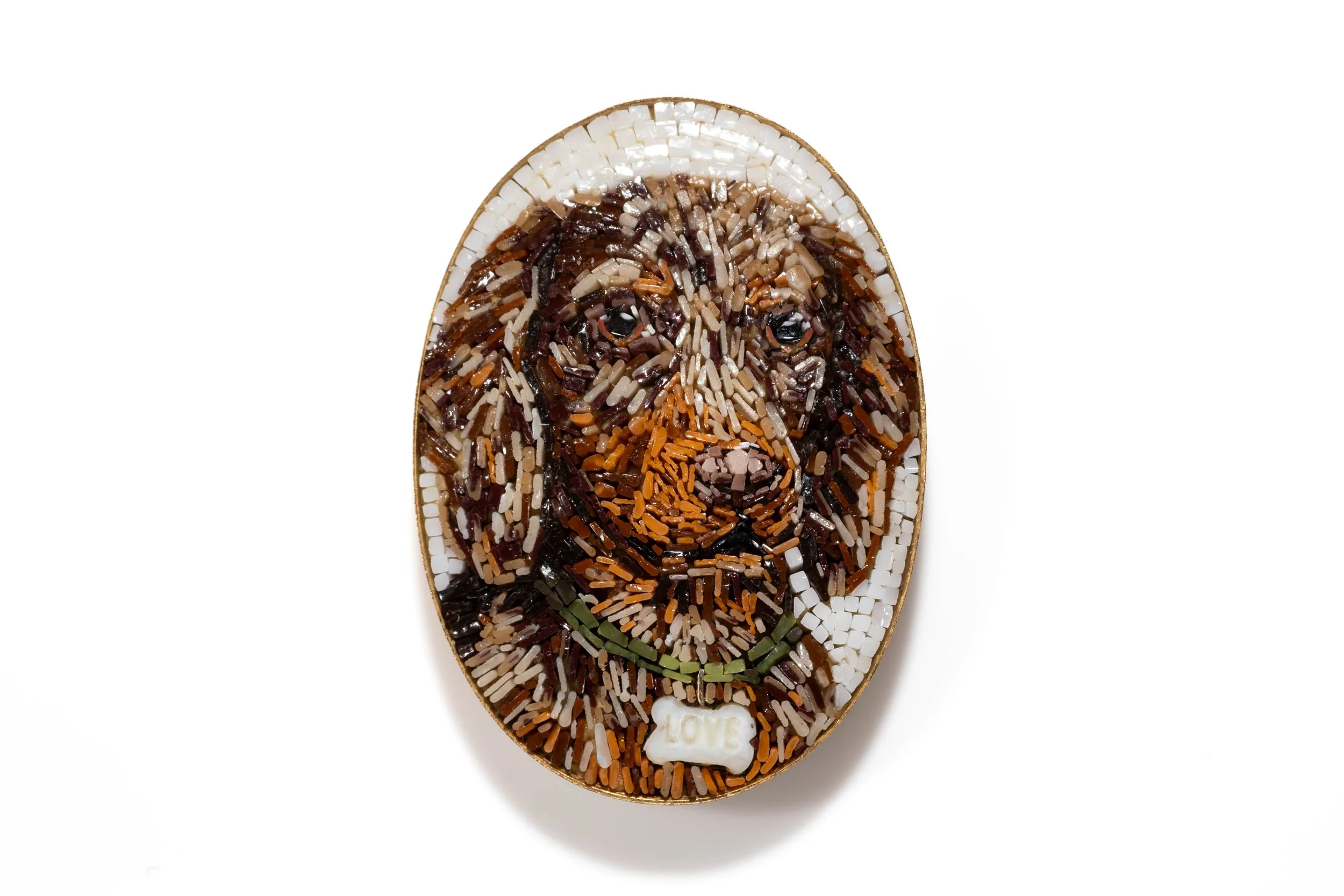 Oval micromosaic portrait of a brown dog with a green collar and bone-shaped tag on a light background.