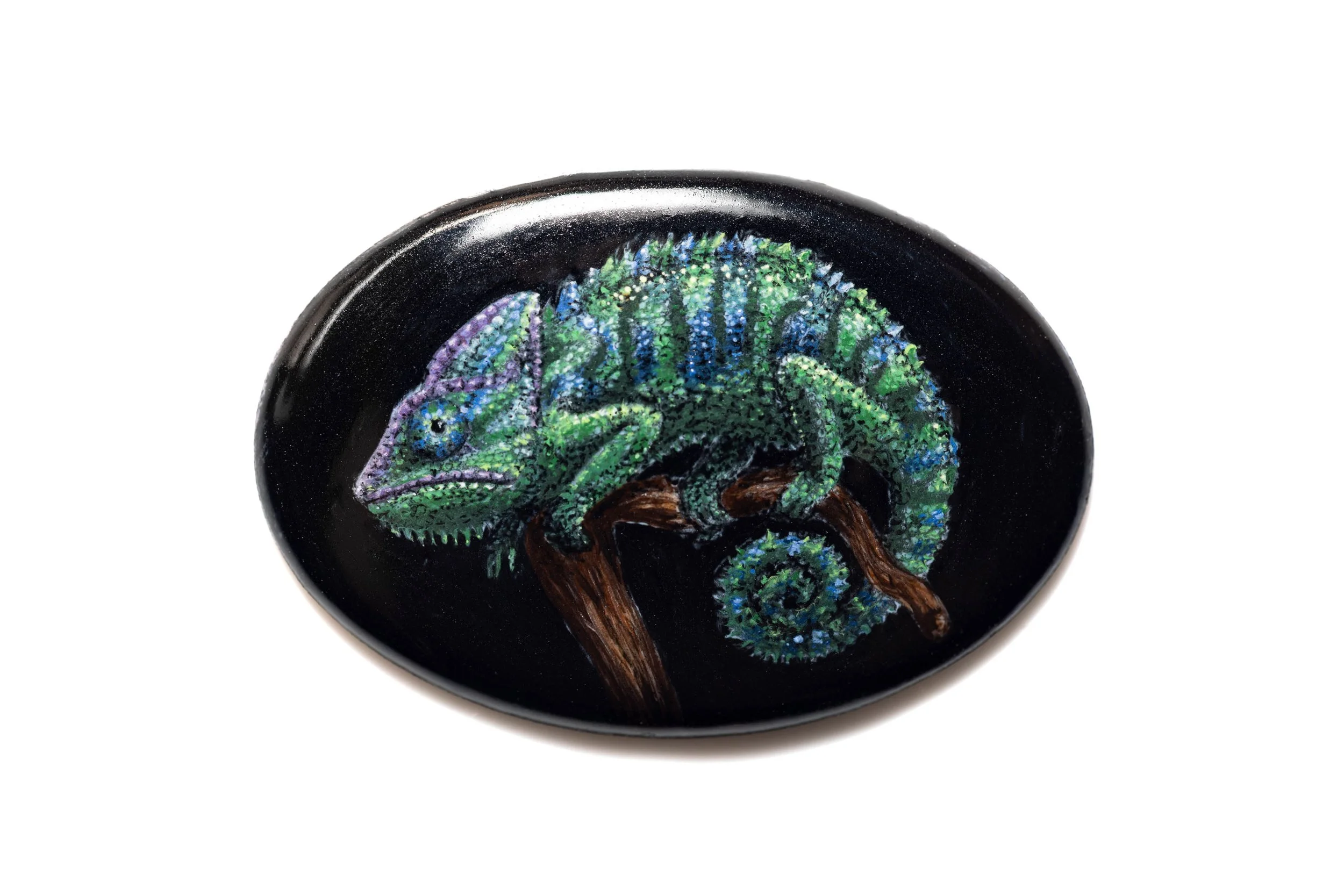 Green and blue chameleon perched on a branch, hand-painted in vitreous enamel on a black oval cabochon.