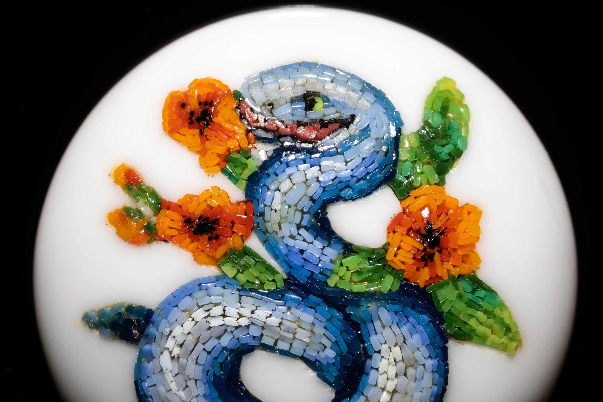 Close-up of the blue snake head and orange flowers, showing individual Murano glass tesserae.