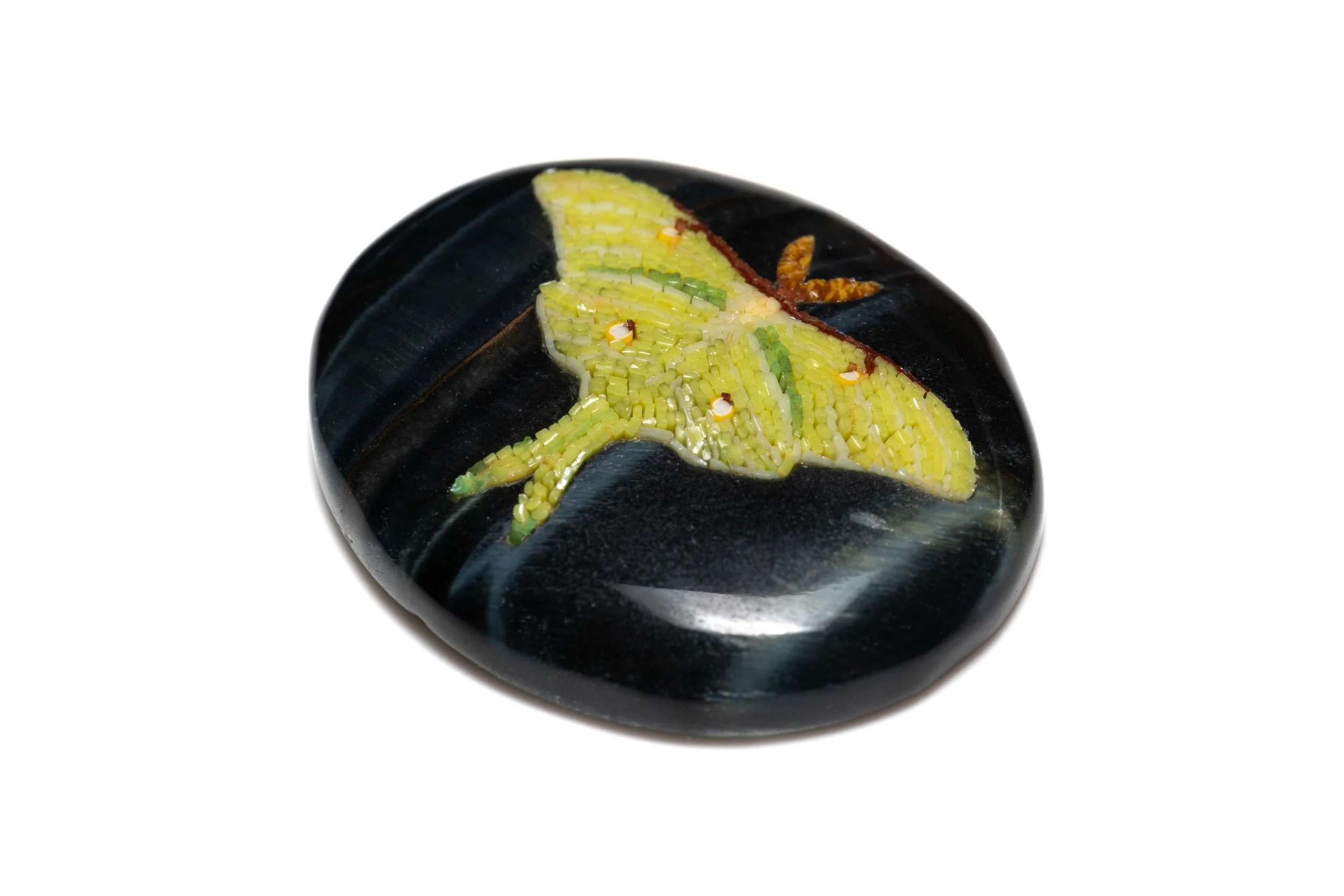 Angled view of the luna moth micromosaic, showing the glass tesserae within its carved black stone base.