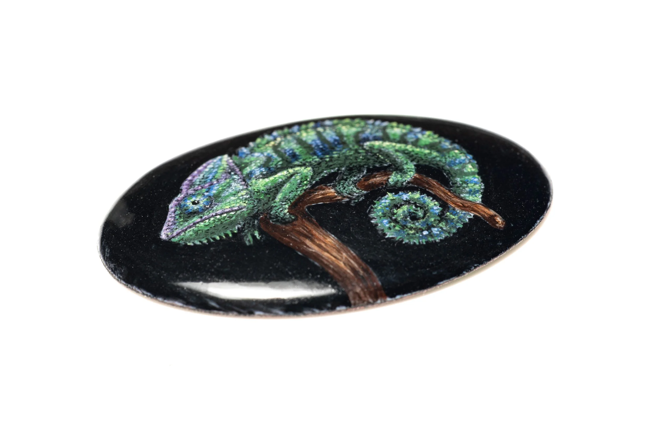 Low angled view of the chameleon enamel cabochon, showing its curved surface and painted branch.