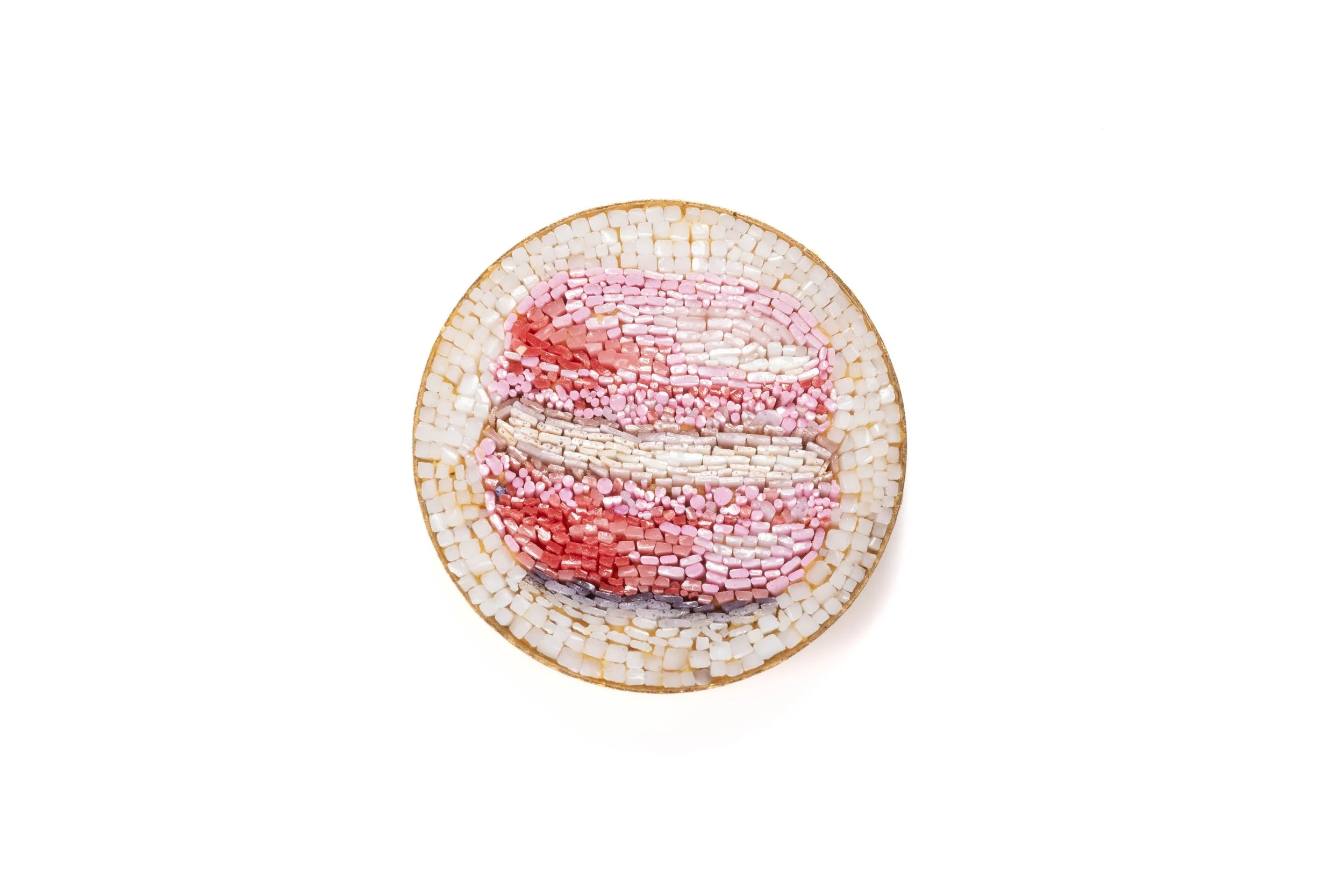 Pink macaron with pale filling in a round micromosaic cabochon on a light background.
