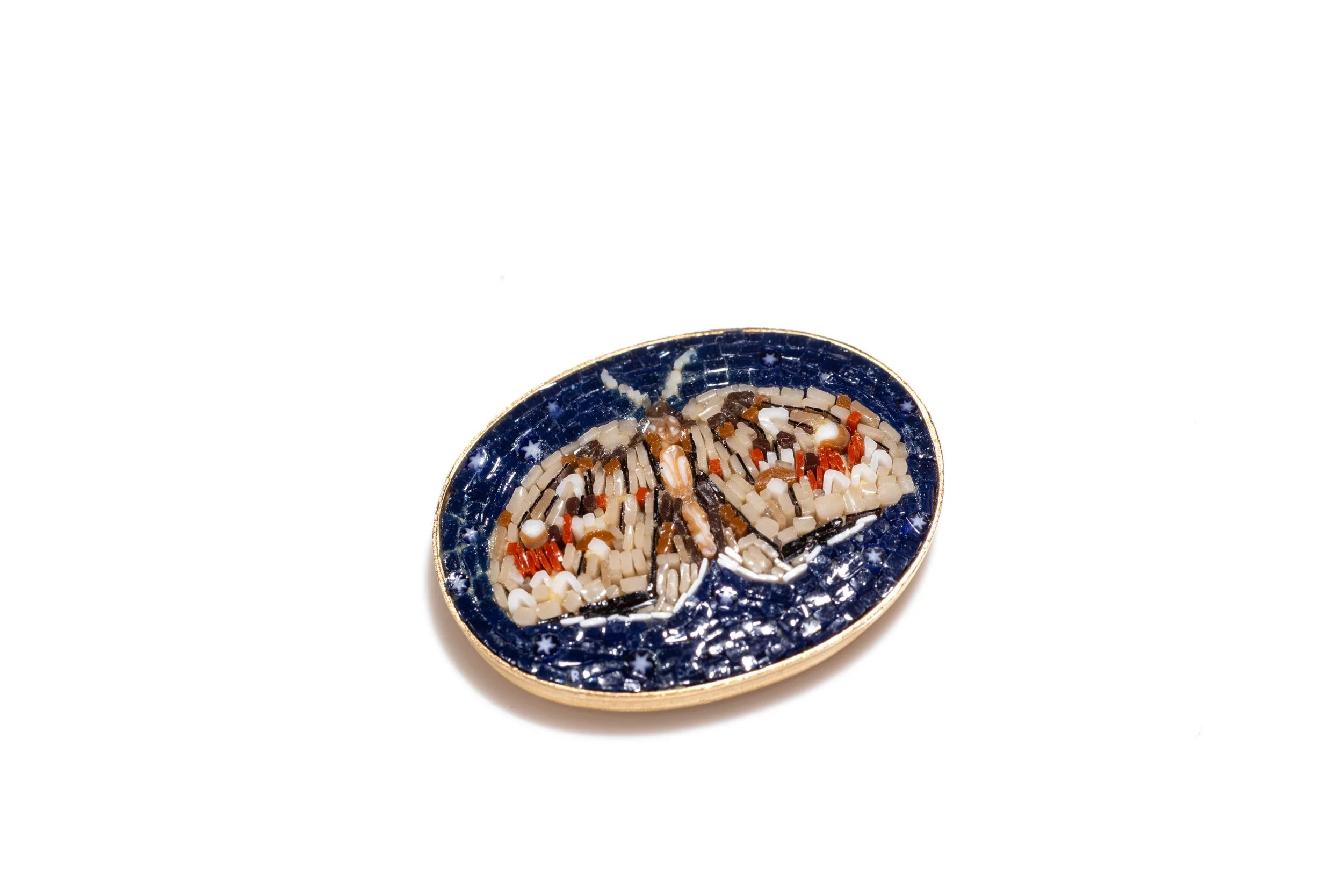 Angled view of the oval moth micromosaic cabochon, showing its raised surface and thin metal edge.