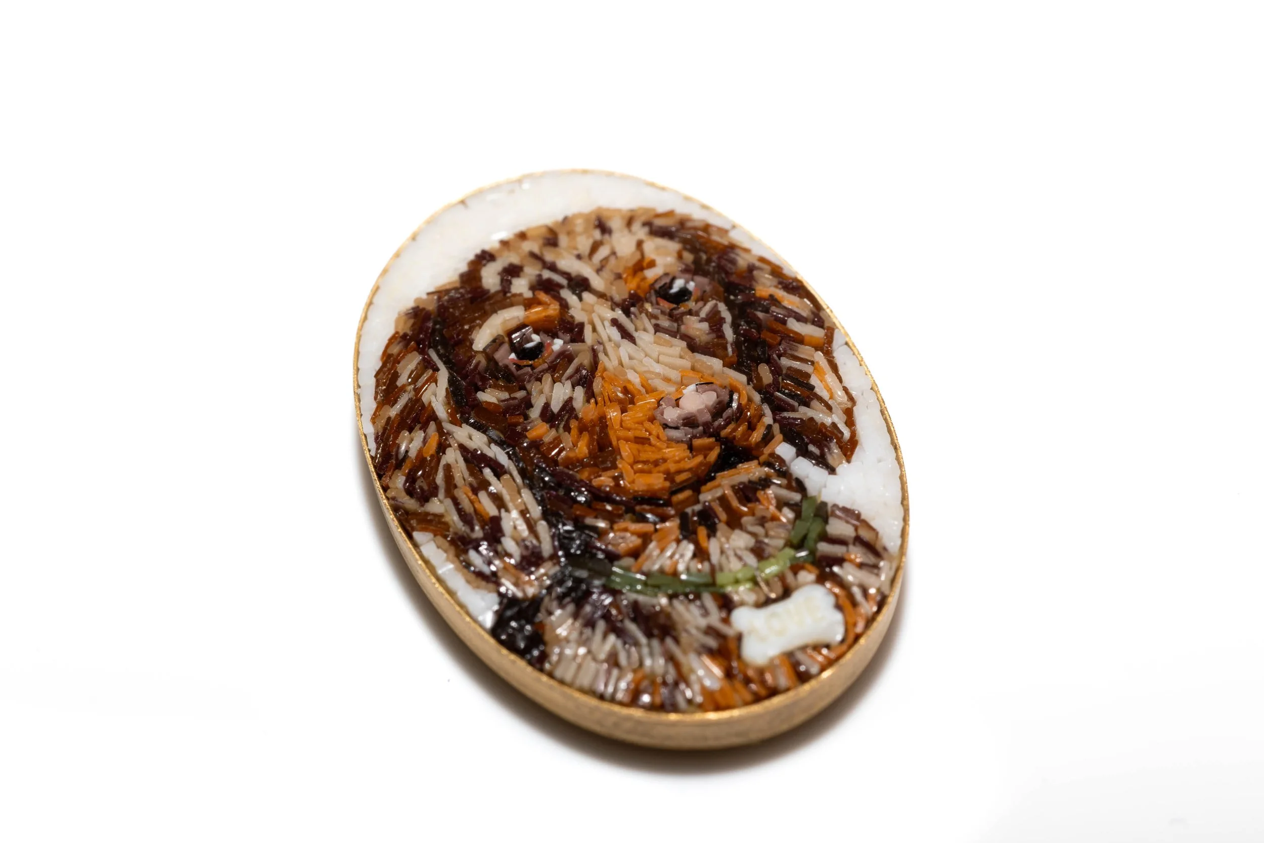 Angled view of the dog portrait micromosaic cabochon, showing its oval shape and metal rim.