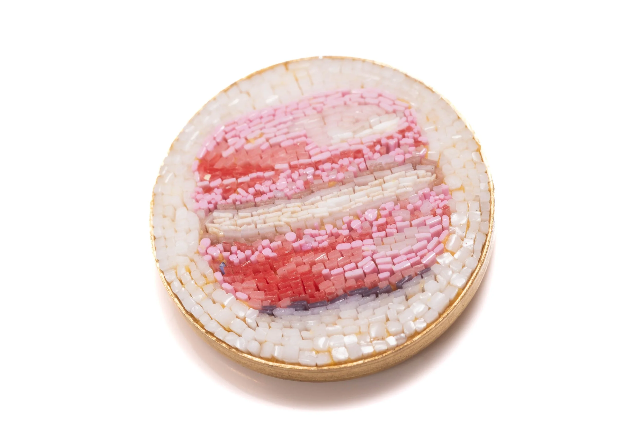 Close angled view of the pink macaron micromosaic, showing the textured glass tesserae and metal rim.