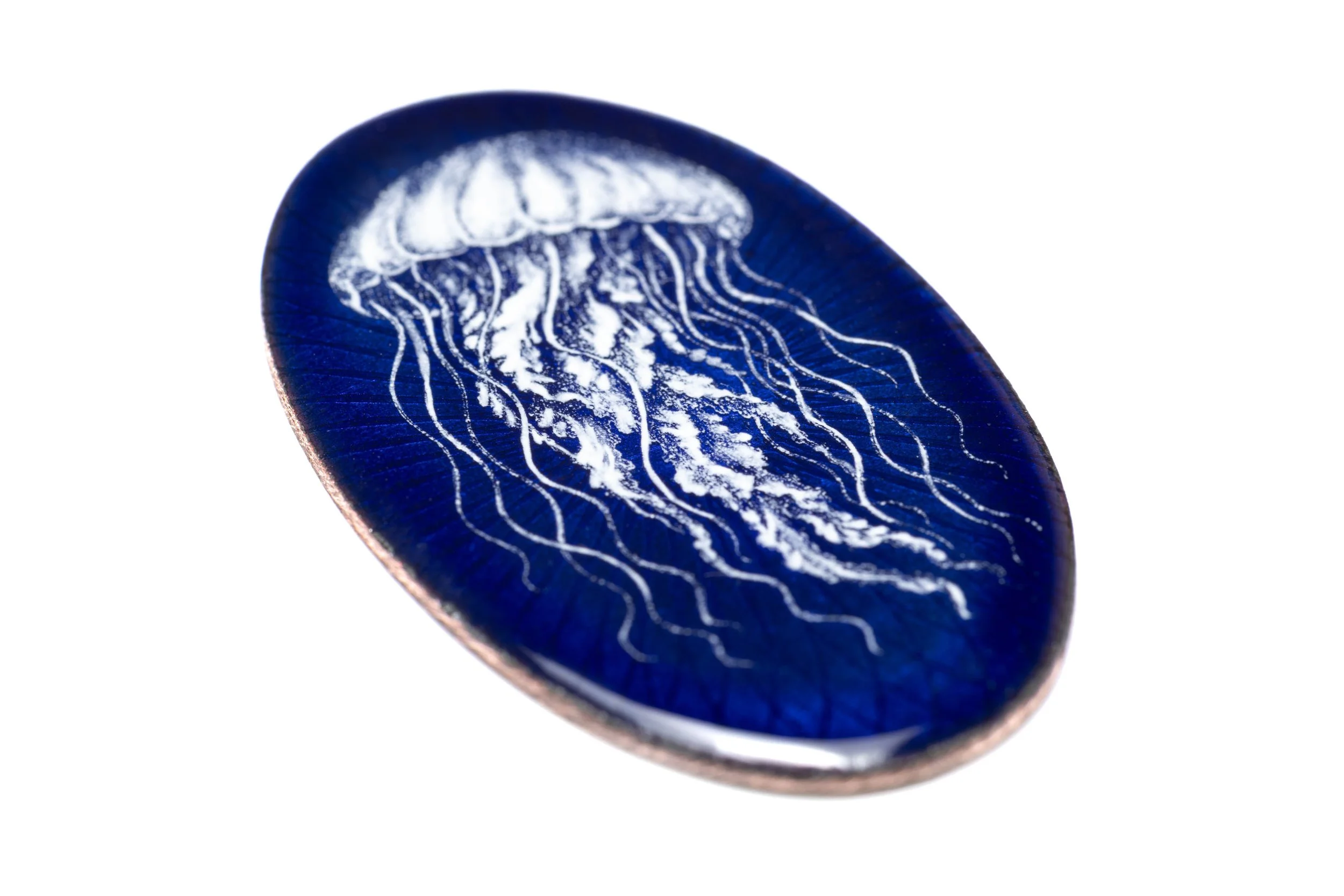 Angled view of the jellyfish grisaille enamel cabochon, showing the reflective blue surface and metal edge.