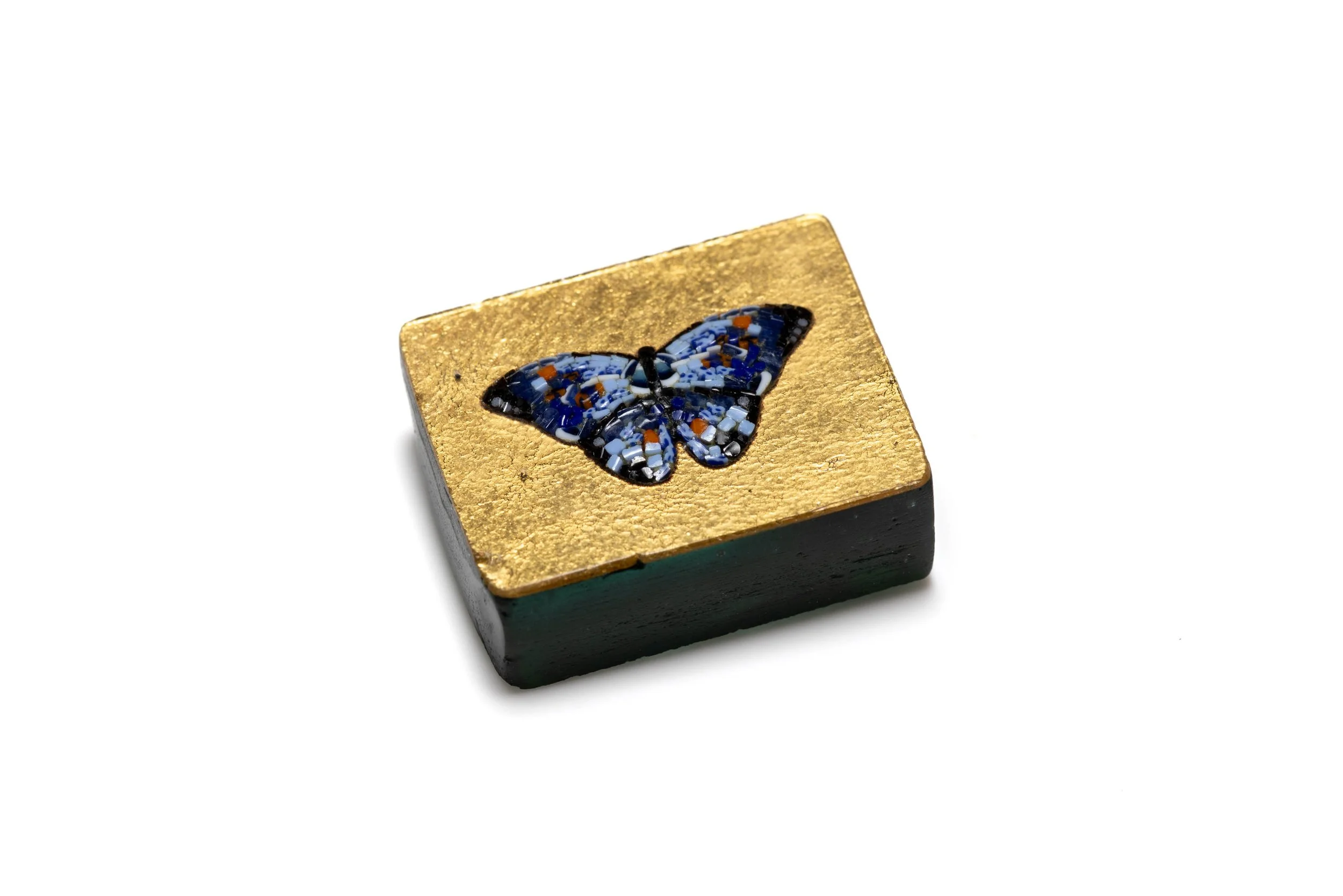 Angled view of the blue butterfly micromosaic cabochon in its carved gold leaf mosaic tile.