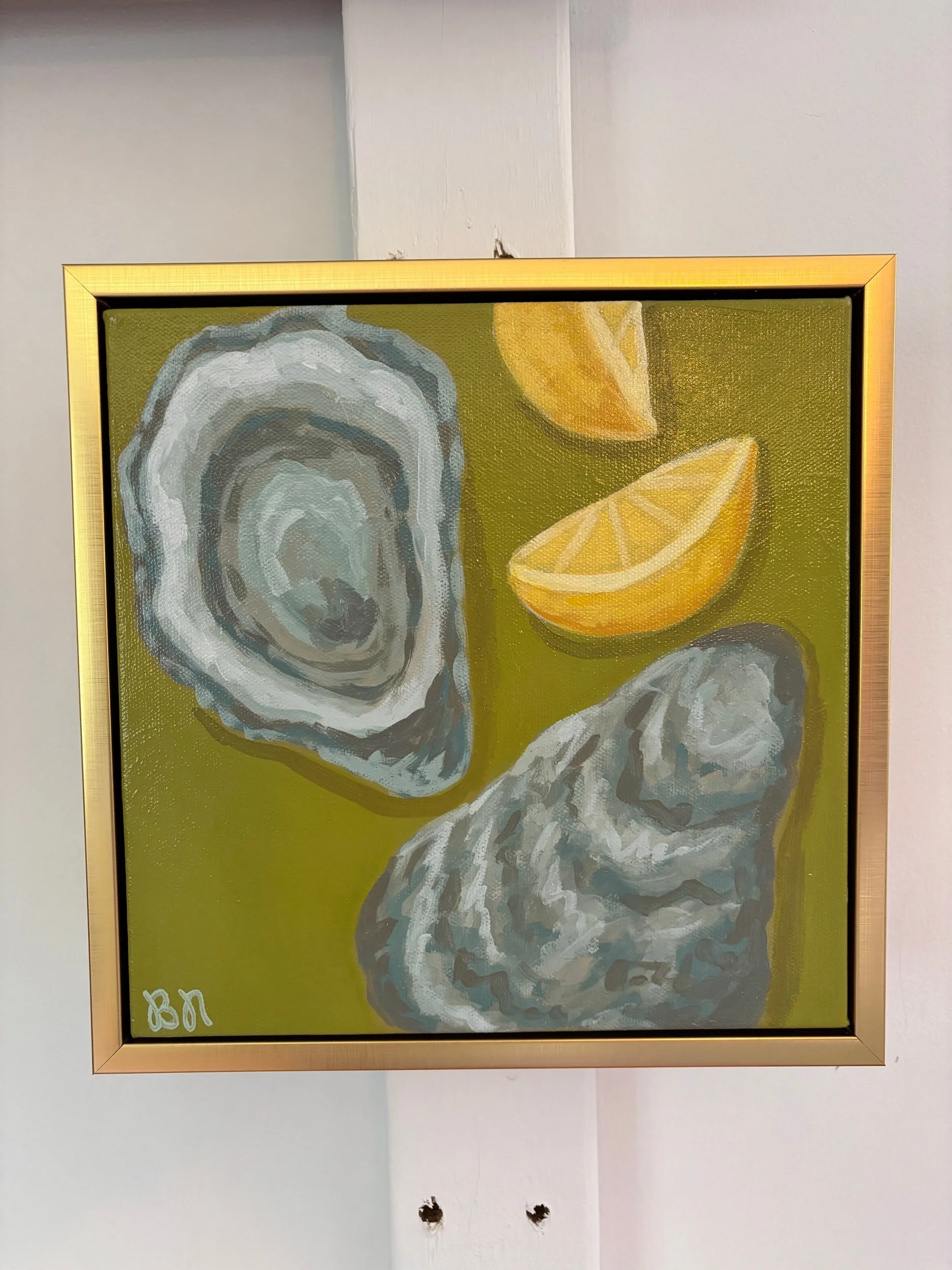 Oyster shell and lemon wedge painting on a rich green background in a gold frame, featuring coastal-inspired acrylic artwork with elegant Southern entertaining style.