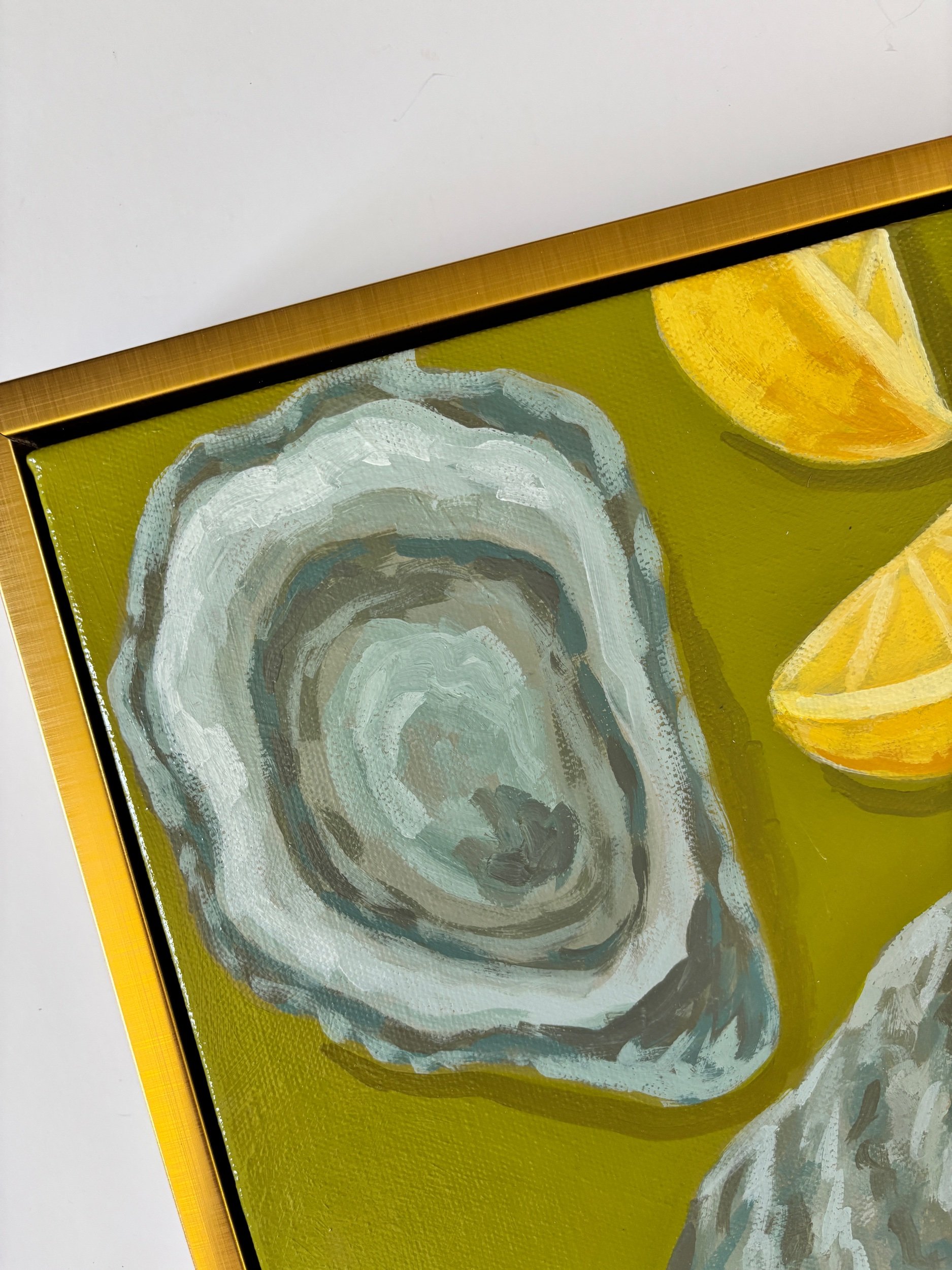 Oyster shell and lemon wedge painting on a rich green background in a gold frame, featuring coastal-inspired acrylic artwork with elegant Southern entertaining style.